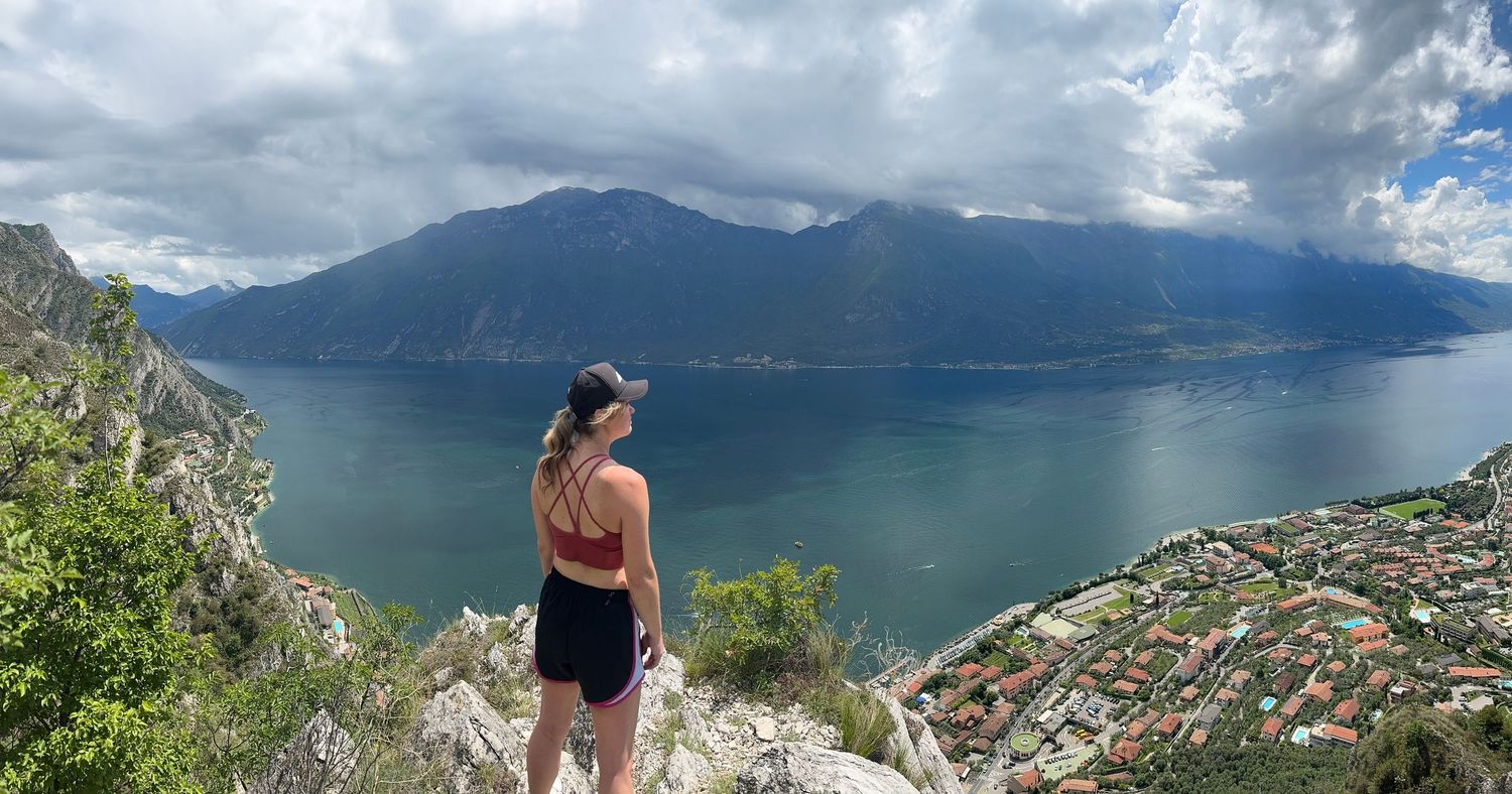 Hiker overlooking scenic mountain lake vista from elevated rocky viewpoint.