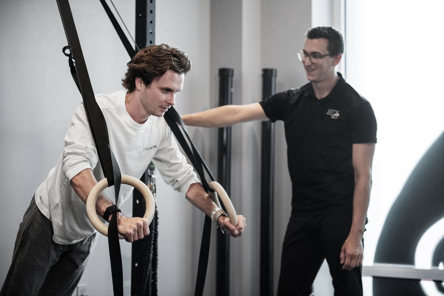 Personal trainer guiding client through suspension training exercise.