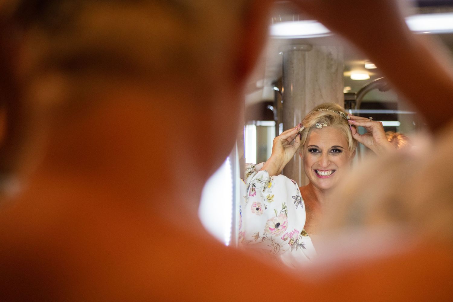 Creative mirror shot captures bride's excited expression during wedding preparations.