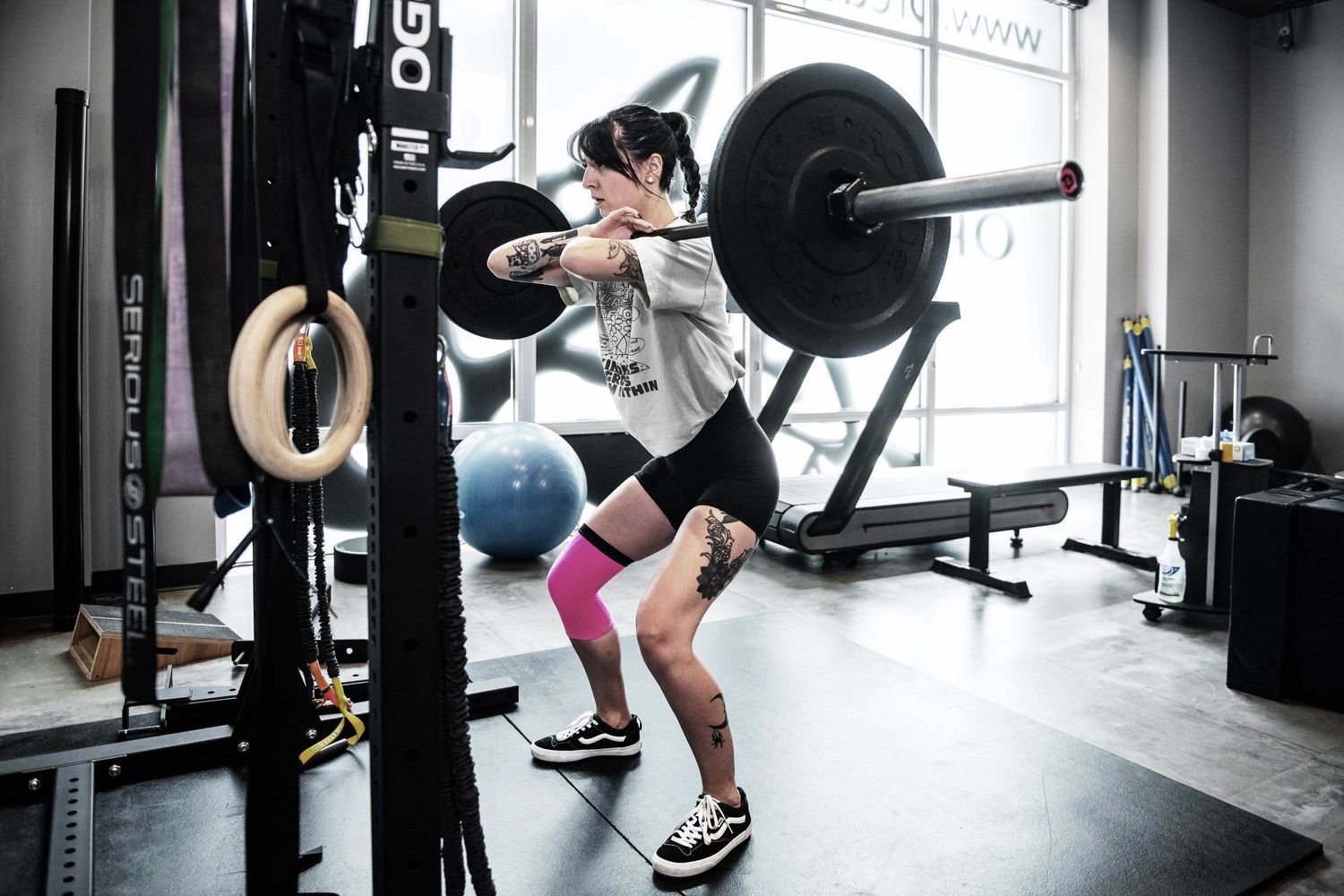 Athlete performing squats with a barbell in a modern gym setting.
