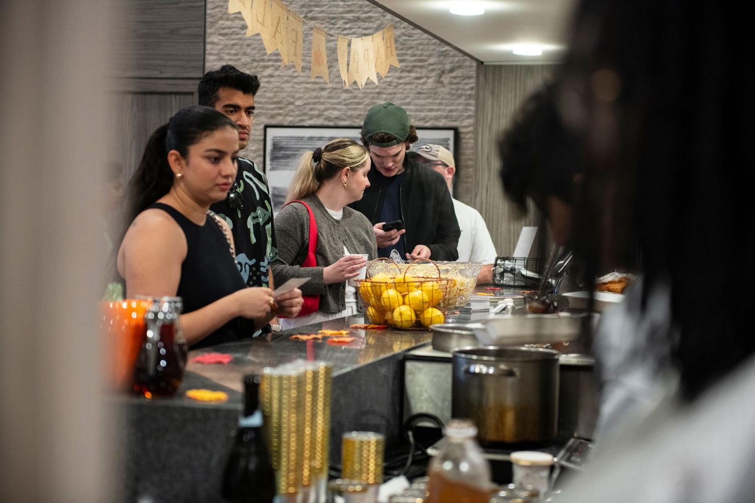 People gathered around buffet station at indoor catered event.