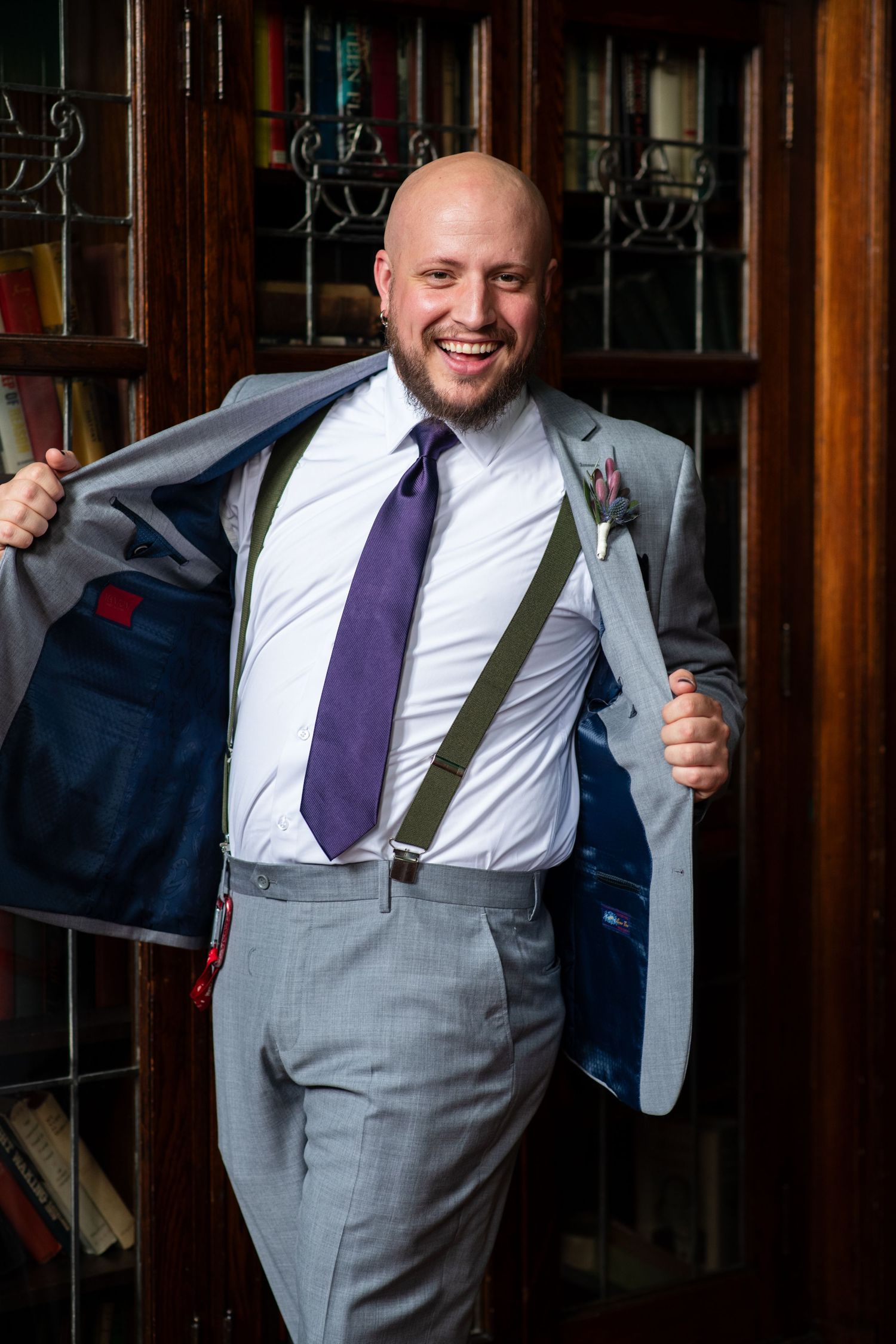 Person in formal attire smiles while showing the navy lining of their gray suit jacket.