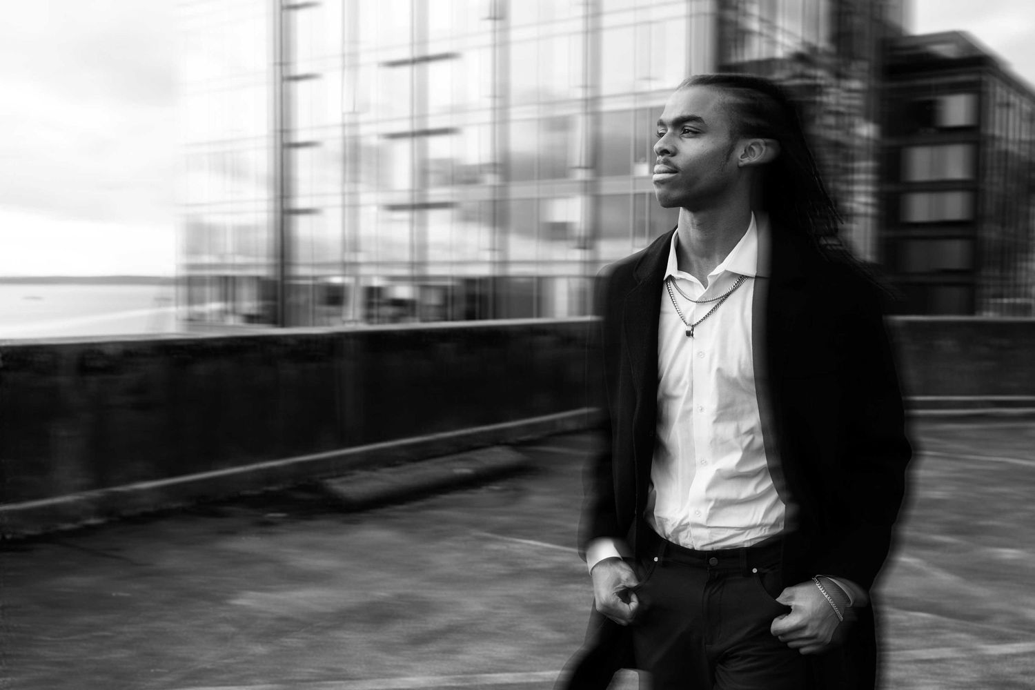 Black and white portrait of a person in a dark jacket and white shirt looking thoughtfully into the distance.