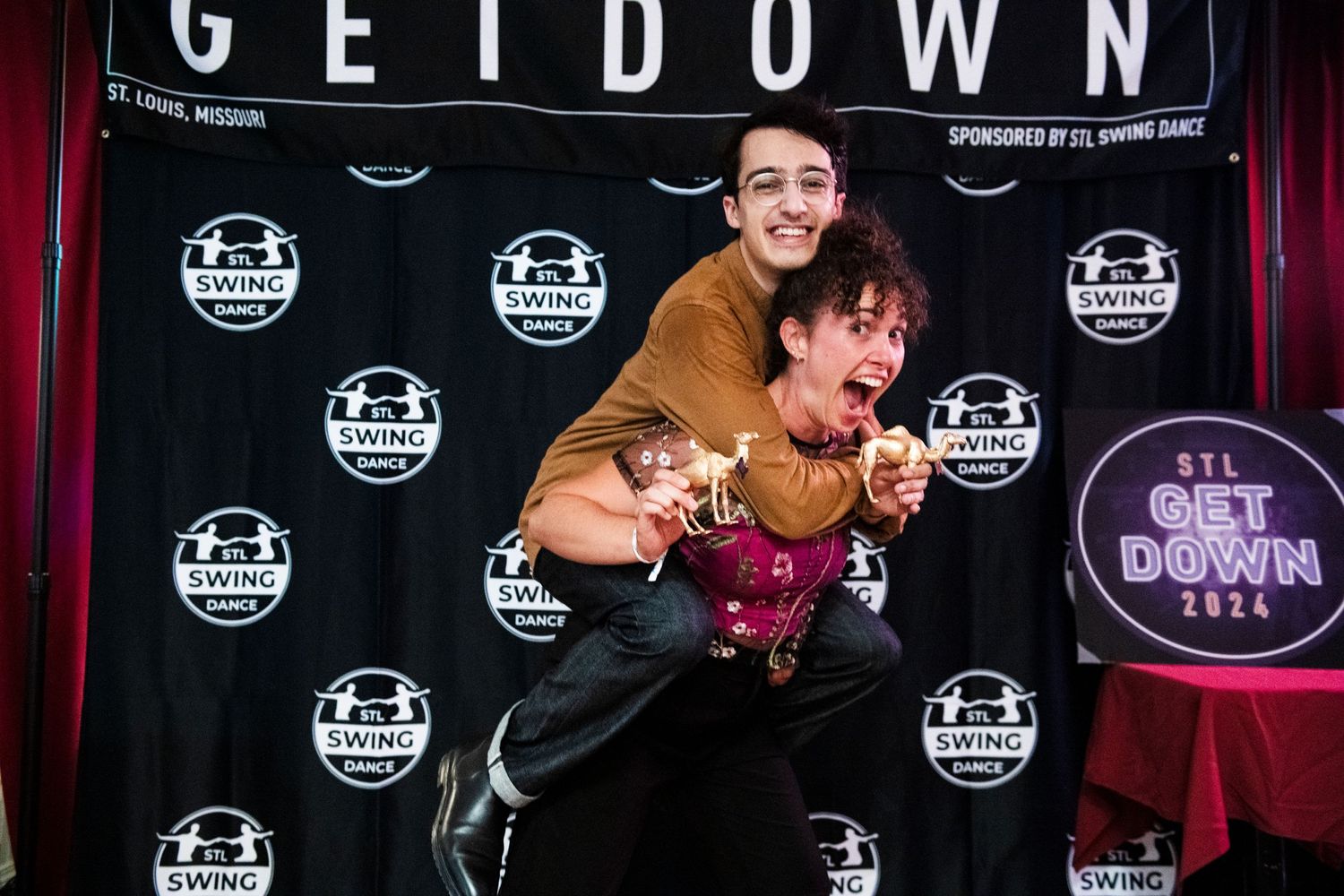 Two people posing playfully in front of a 'GET DOWN' event backdrop.