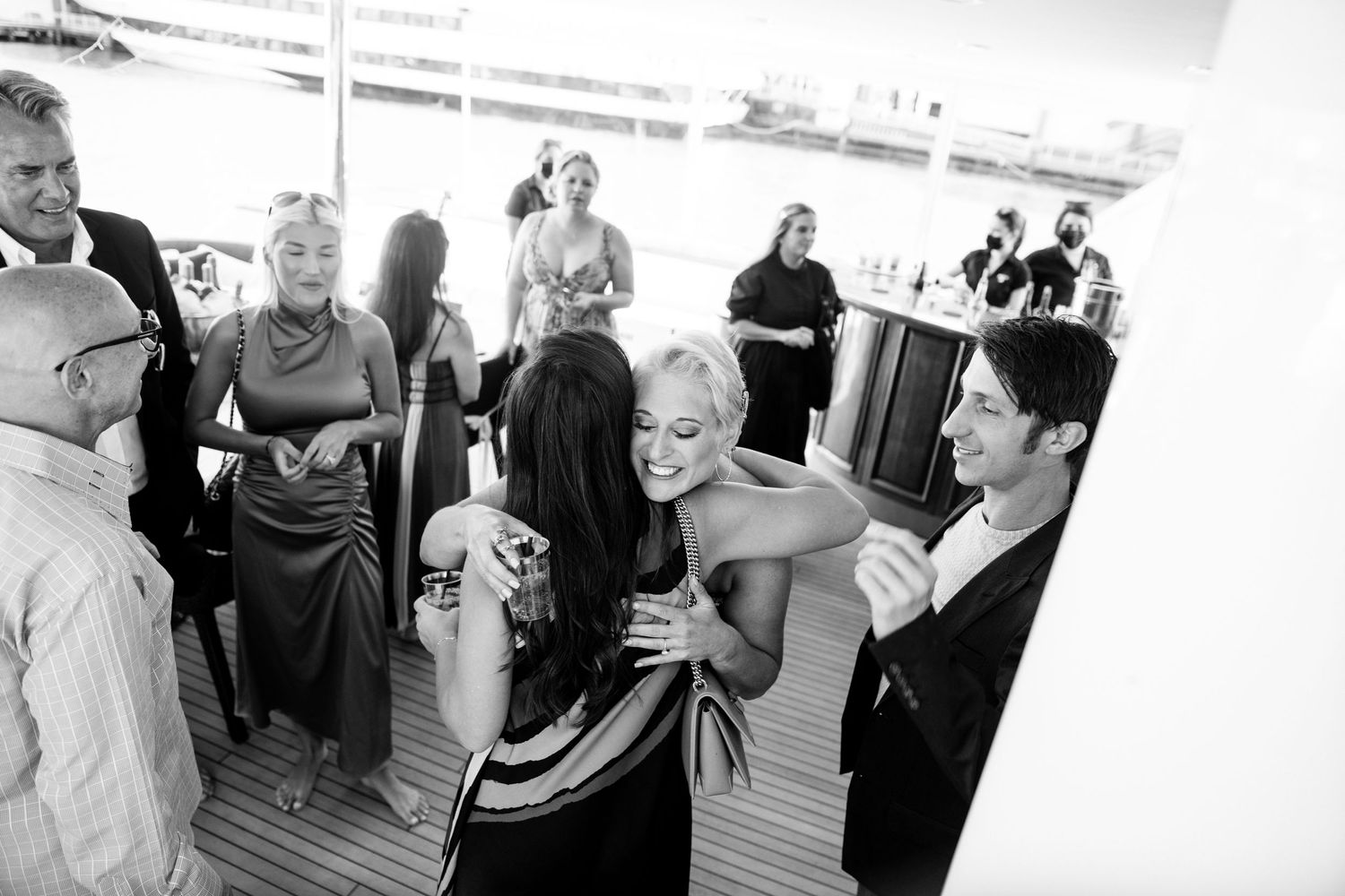 Black and white candid photo of guests dancing and socializing at a boat party.