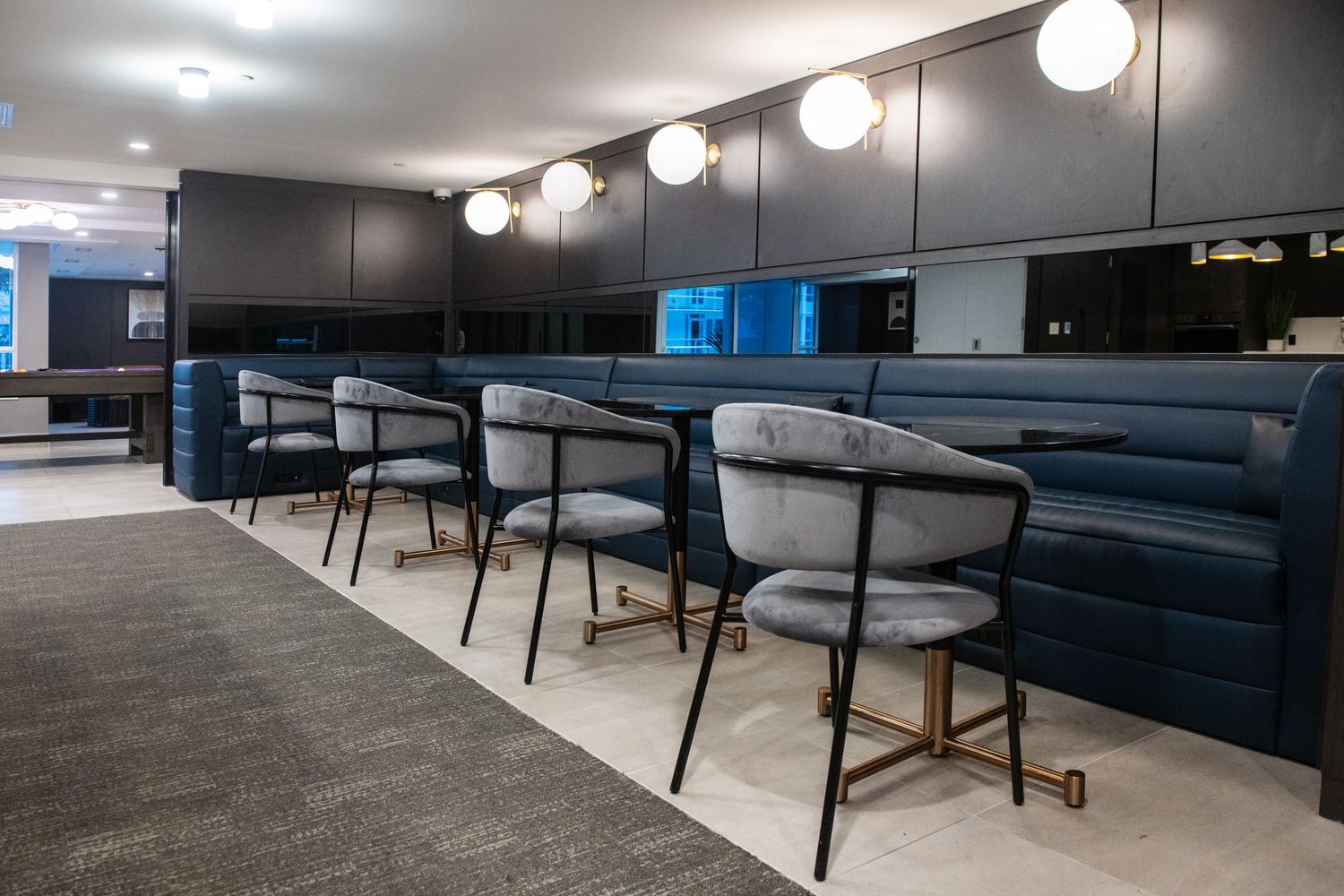 Sleek bar-style seating area with globe lights and dark modern decor in community space.