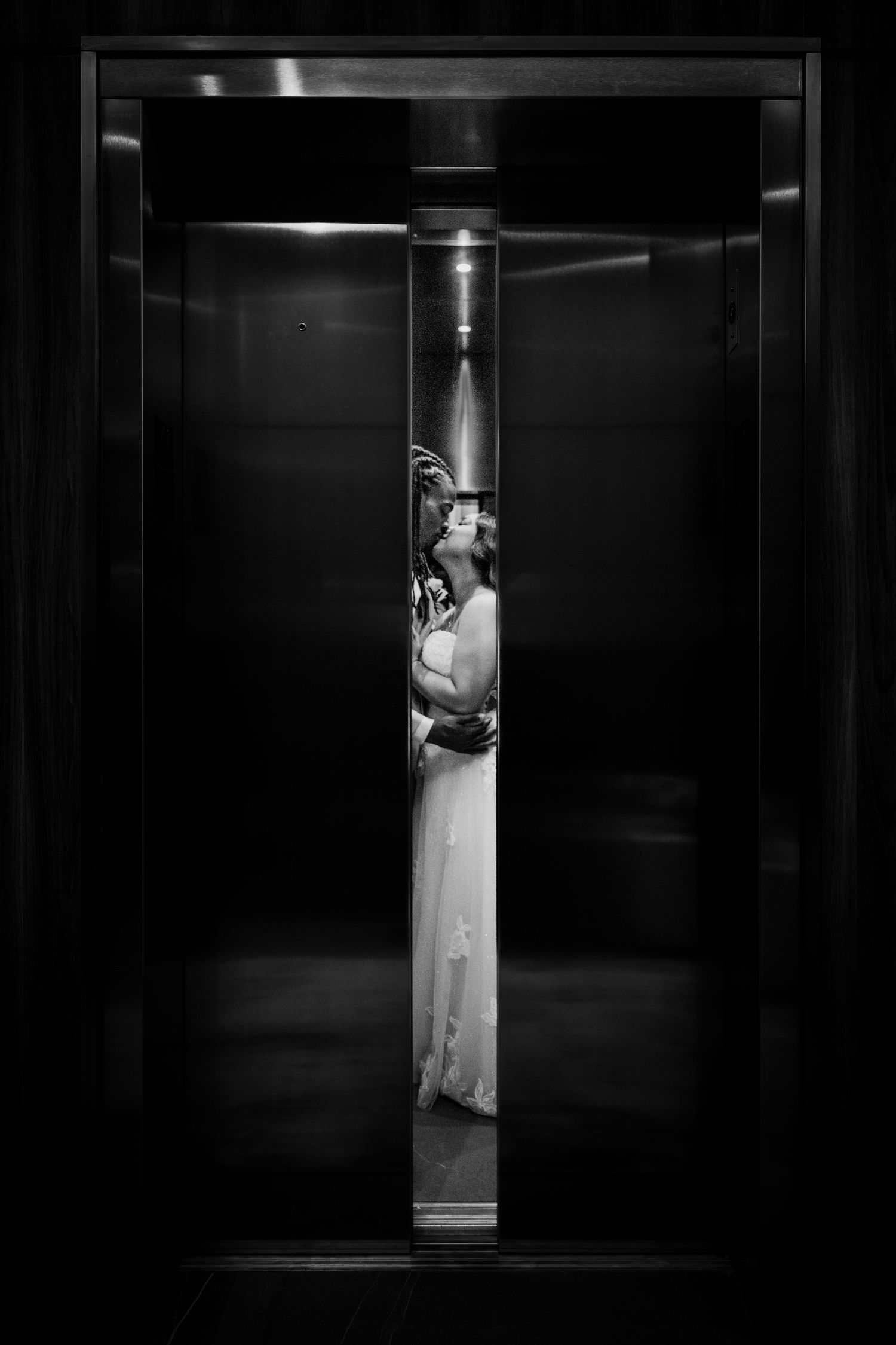 A black and white series showing a bride in white dress inside a dark elevator with dramatic lighting.