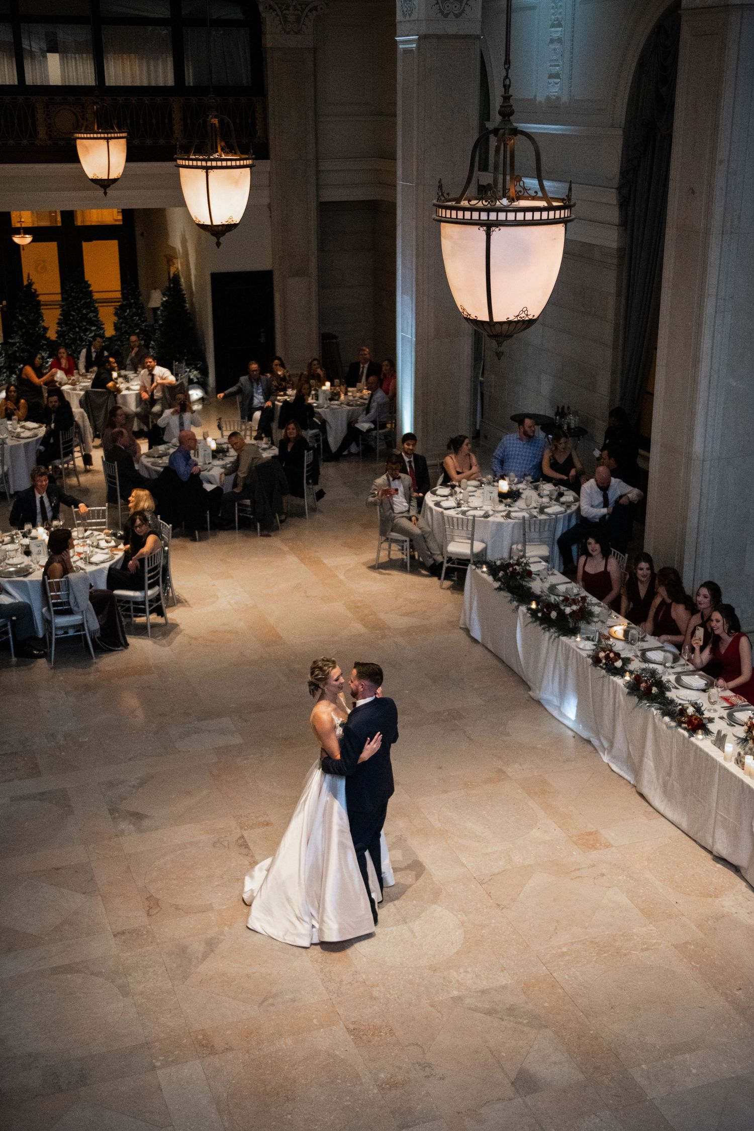 Elegant ballroom reception with hanging lanterns illuminating dancers and dining tables.
