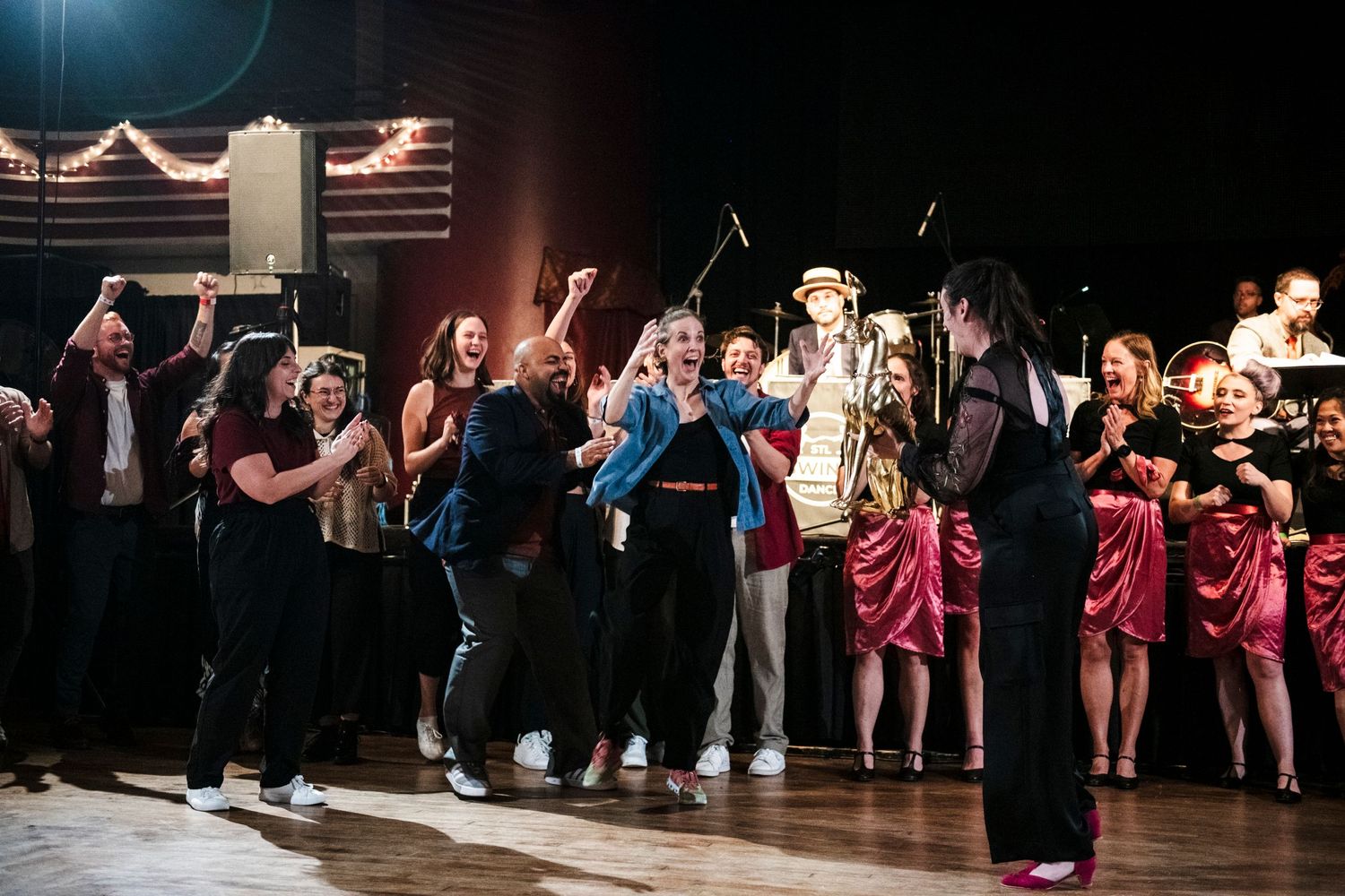 Large group of performers dancing and celebrating on stage during an energetic show.