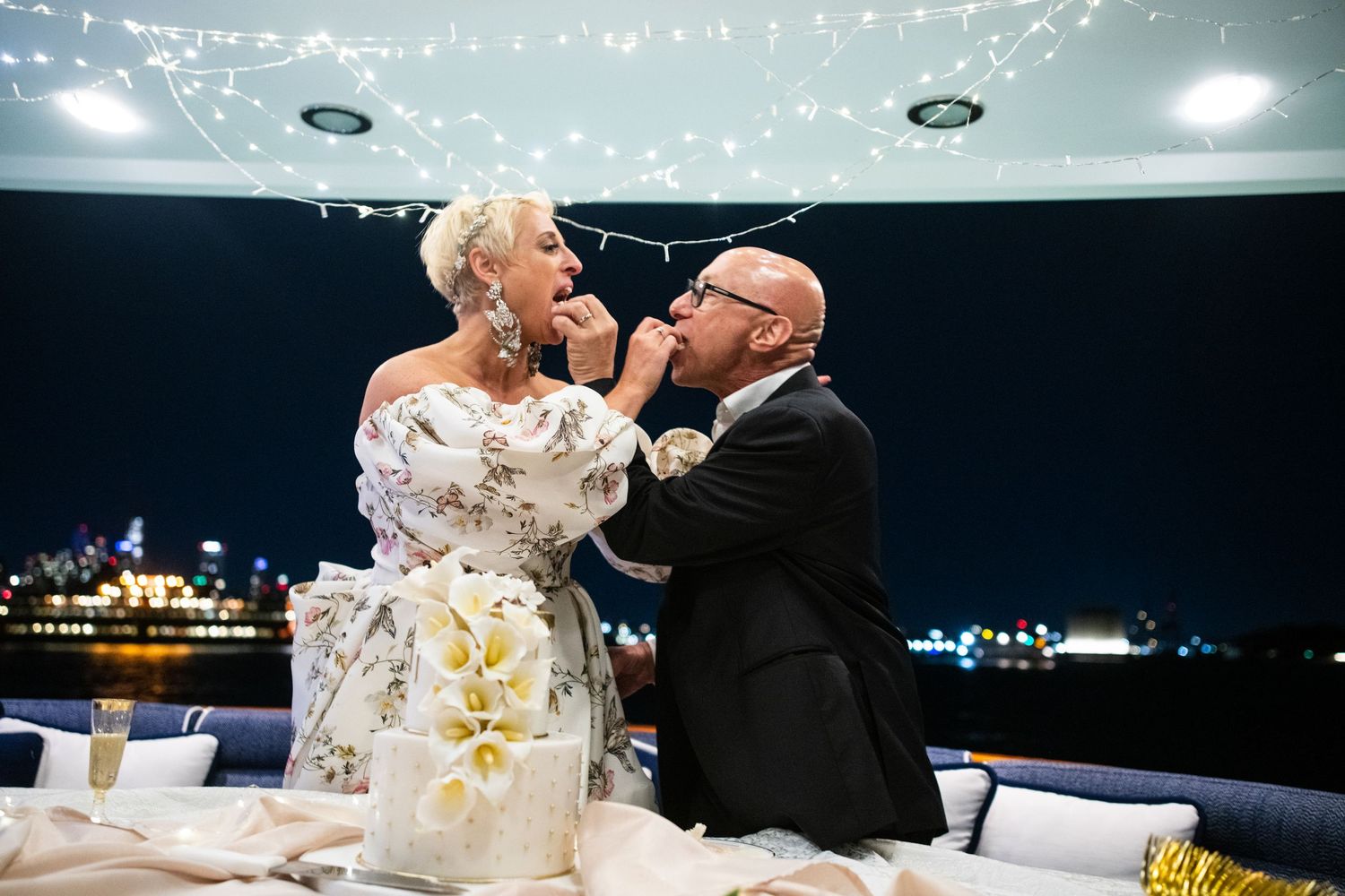 Newlyweds playfully feed each other wedding cake during their reception celebration.