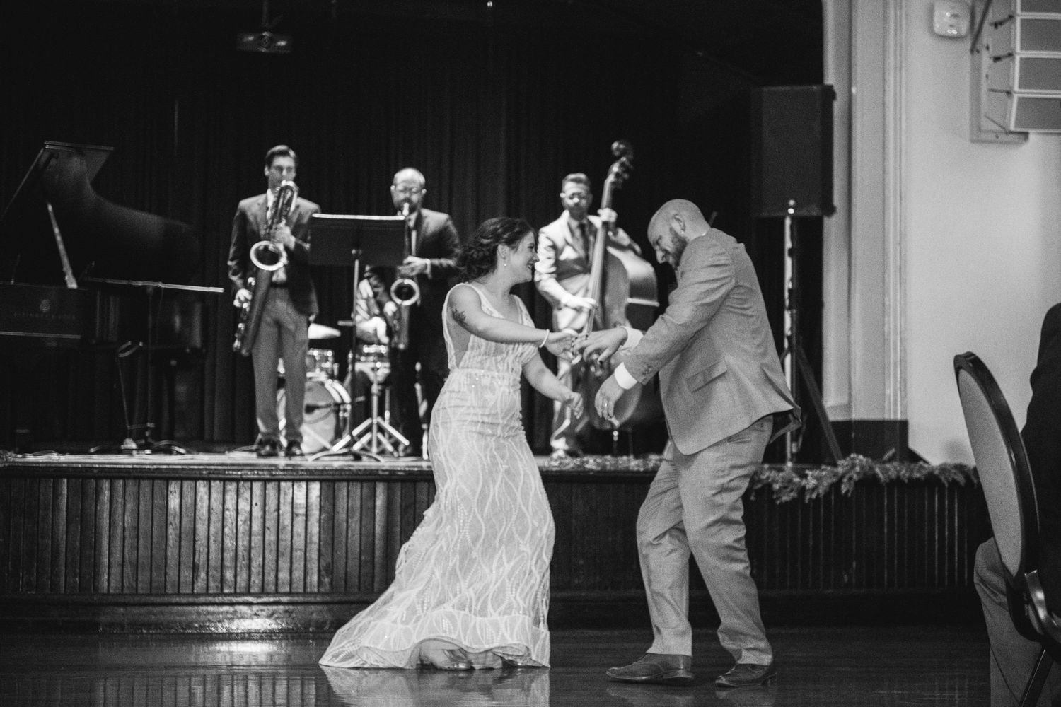 A black and white photo of a couple dancing with a live band performing on stage.