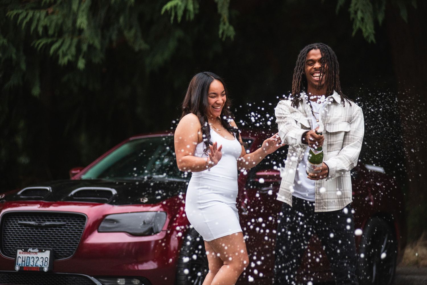 Happy couple splashes water and laughs together during an outdoor engagement photo session.