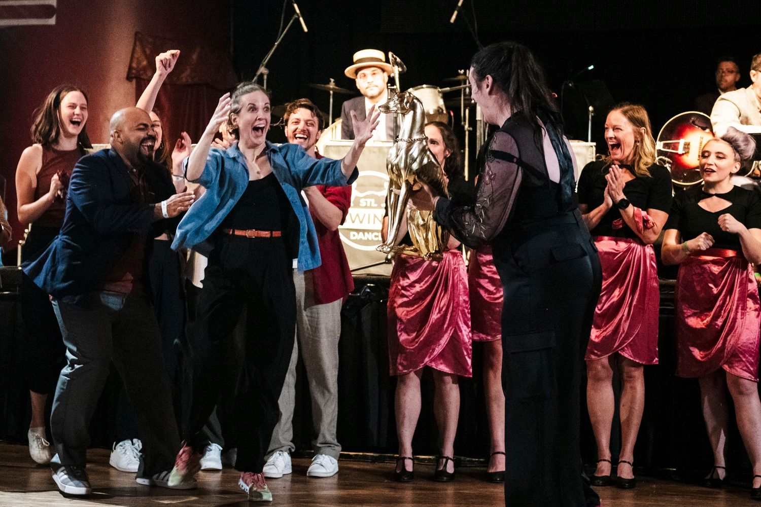 Enthusiastic performers celebrate during a show finale with vintage stage decorations.