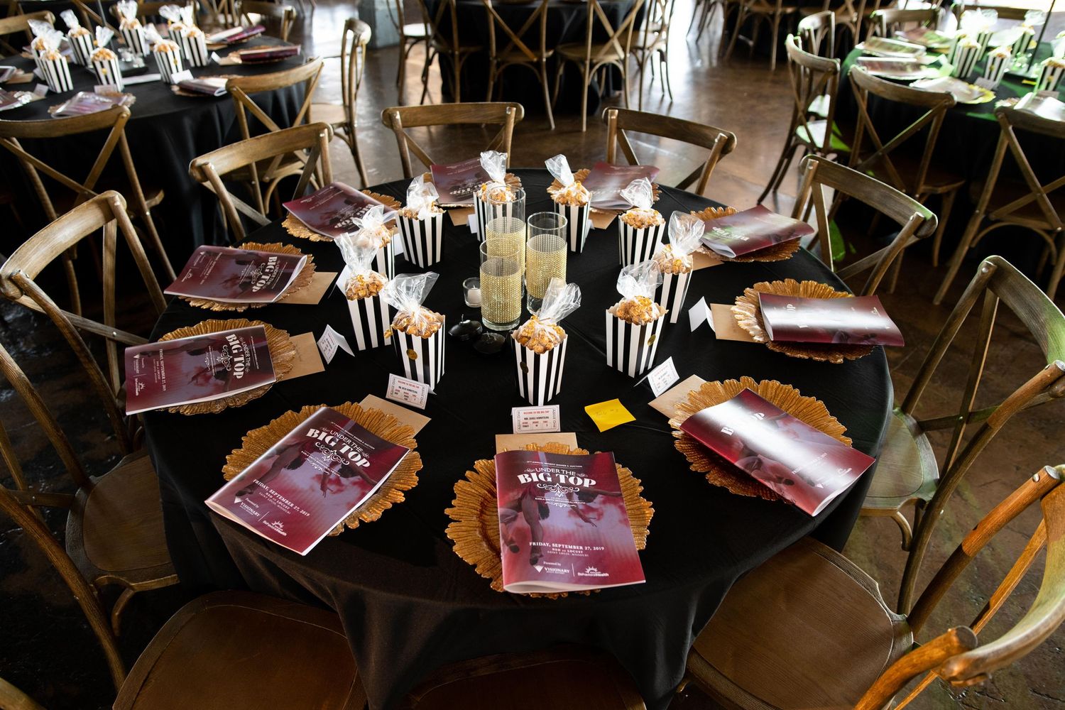 Round dining table decorated with black and white striped elements and tall white feather centerpieces.