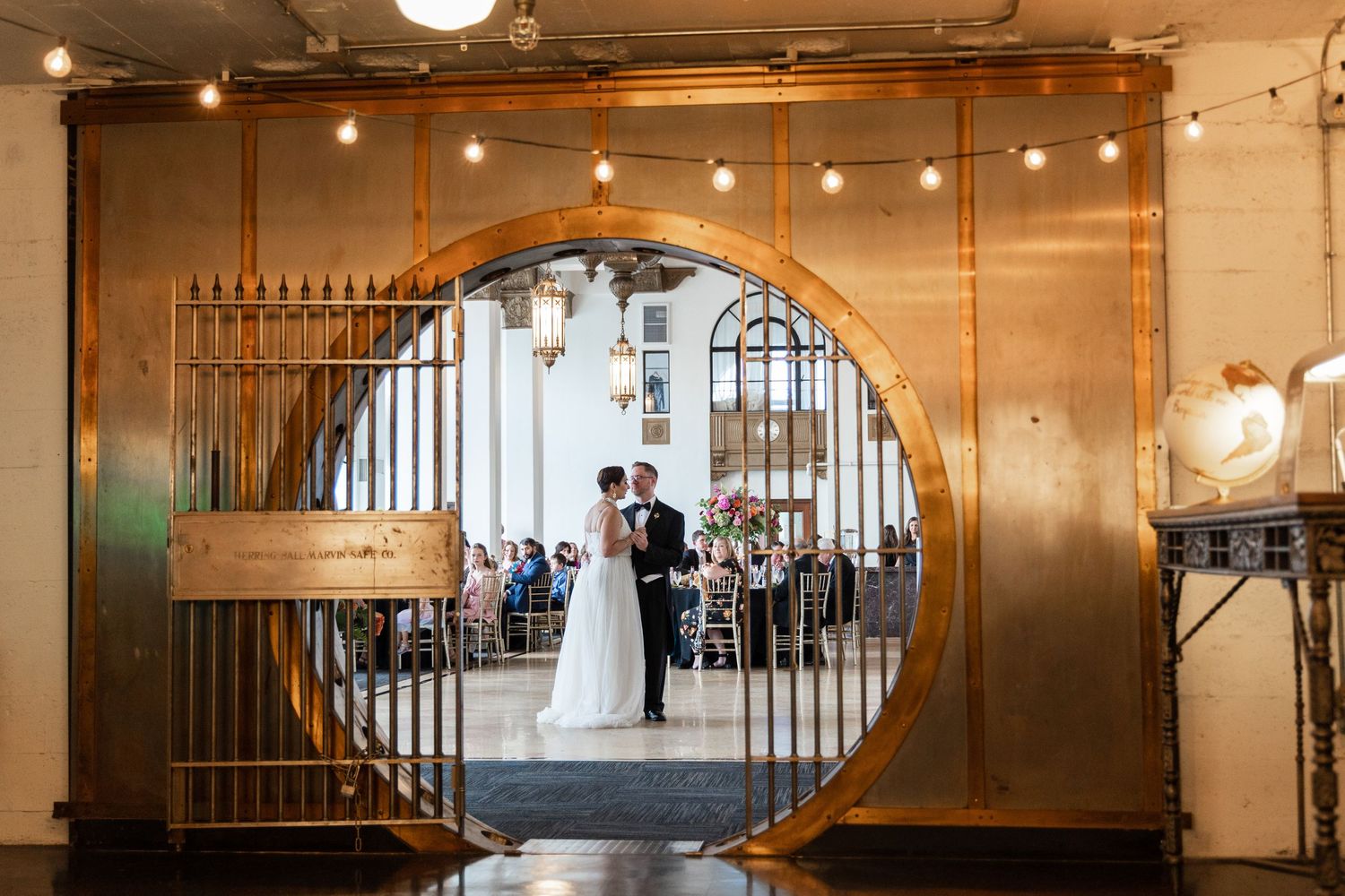Wedding ceremony setup viewed through circular archway with string lights.