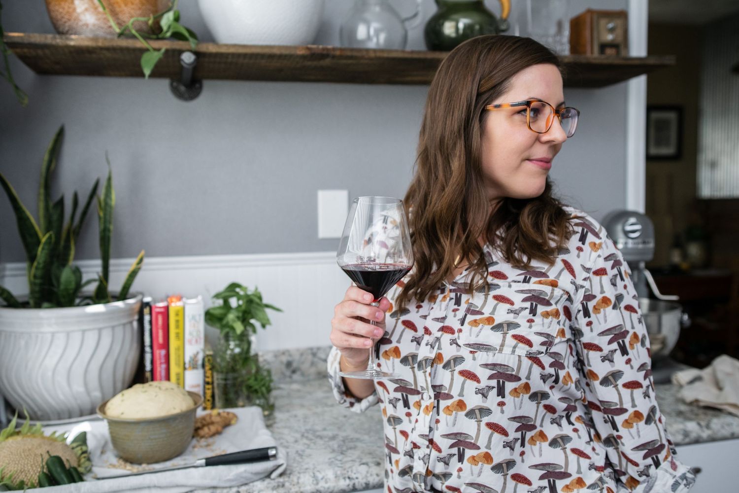 A person enjoying a glass of red wine in a modern kitchen with open shelving.