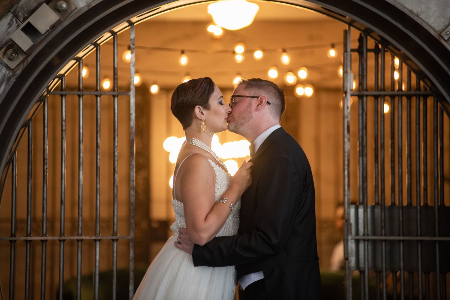 A romantic moment between a couple in front of an illuminated vault entrance.