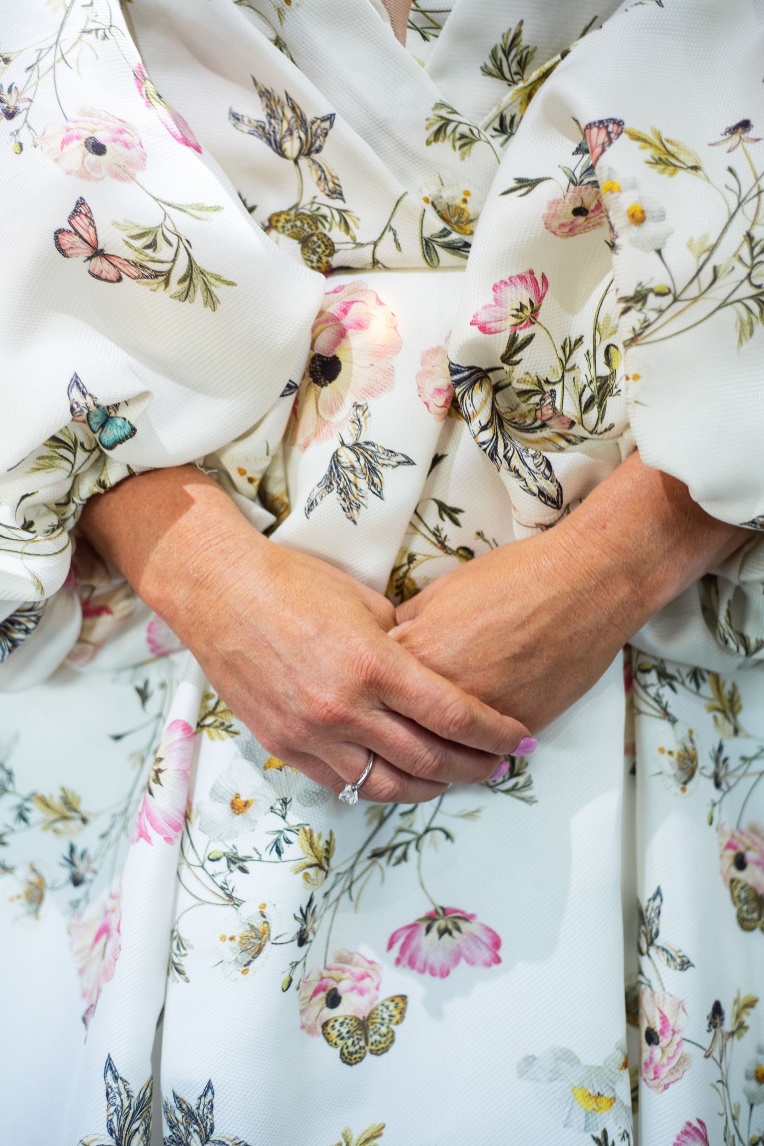 Close-up of delicate floral print fabric with butterflies and pink flowers on white background.