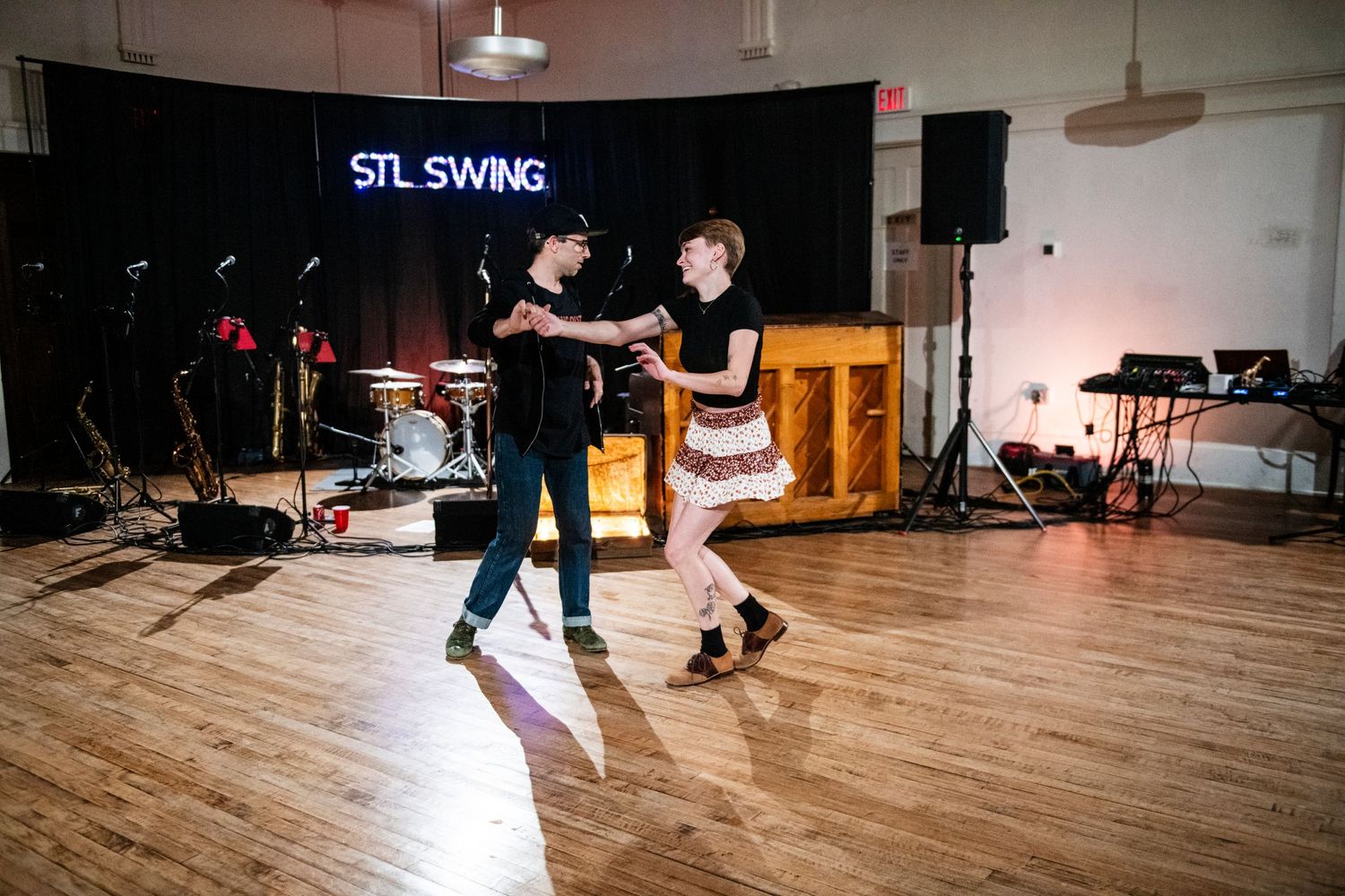Dance partners execute synchronized swing steps on polished wooden floor.
