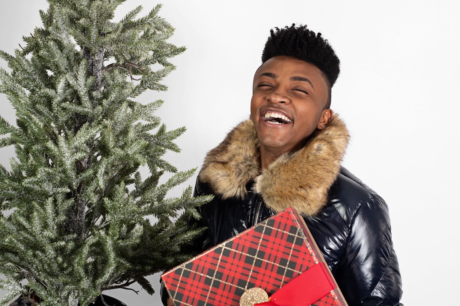 Holiday fashion shoot with Christmas tree and plaid wrapped present.
