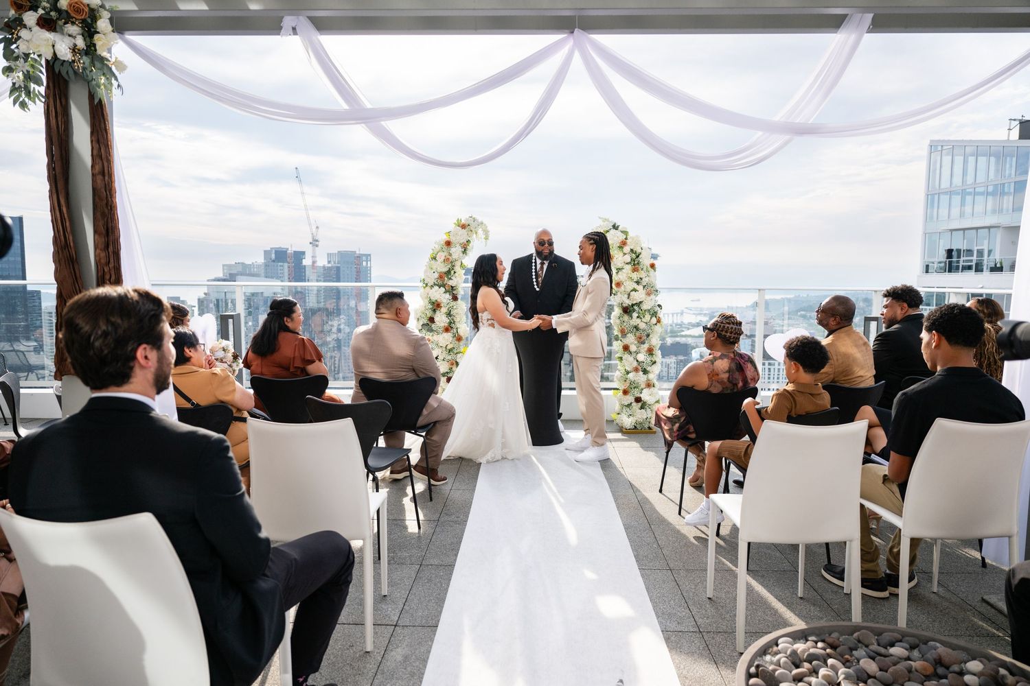 Modern rooftop wedding venue setup with white chairs and decorations against a city skyline.