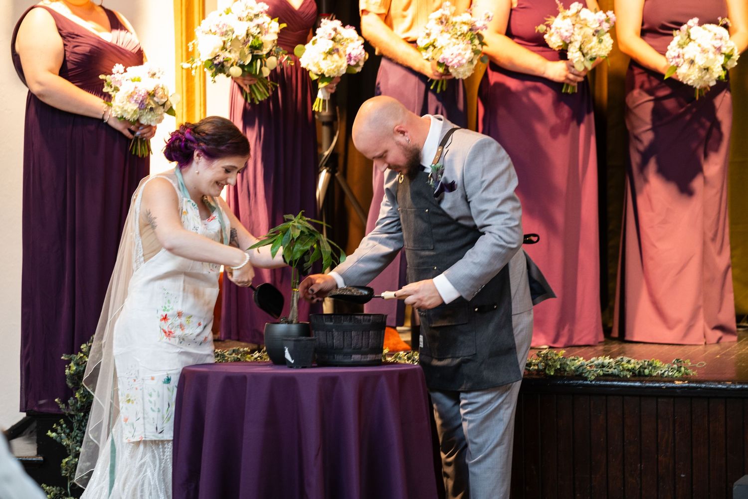 Couple performs a unity ceremony at their wedding with burgundy-dressed attendants.