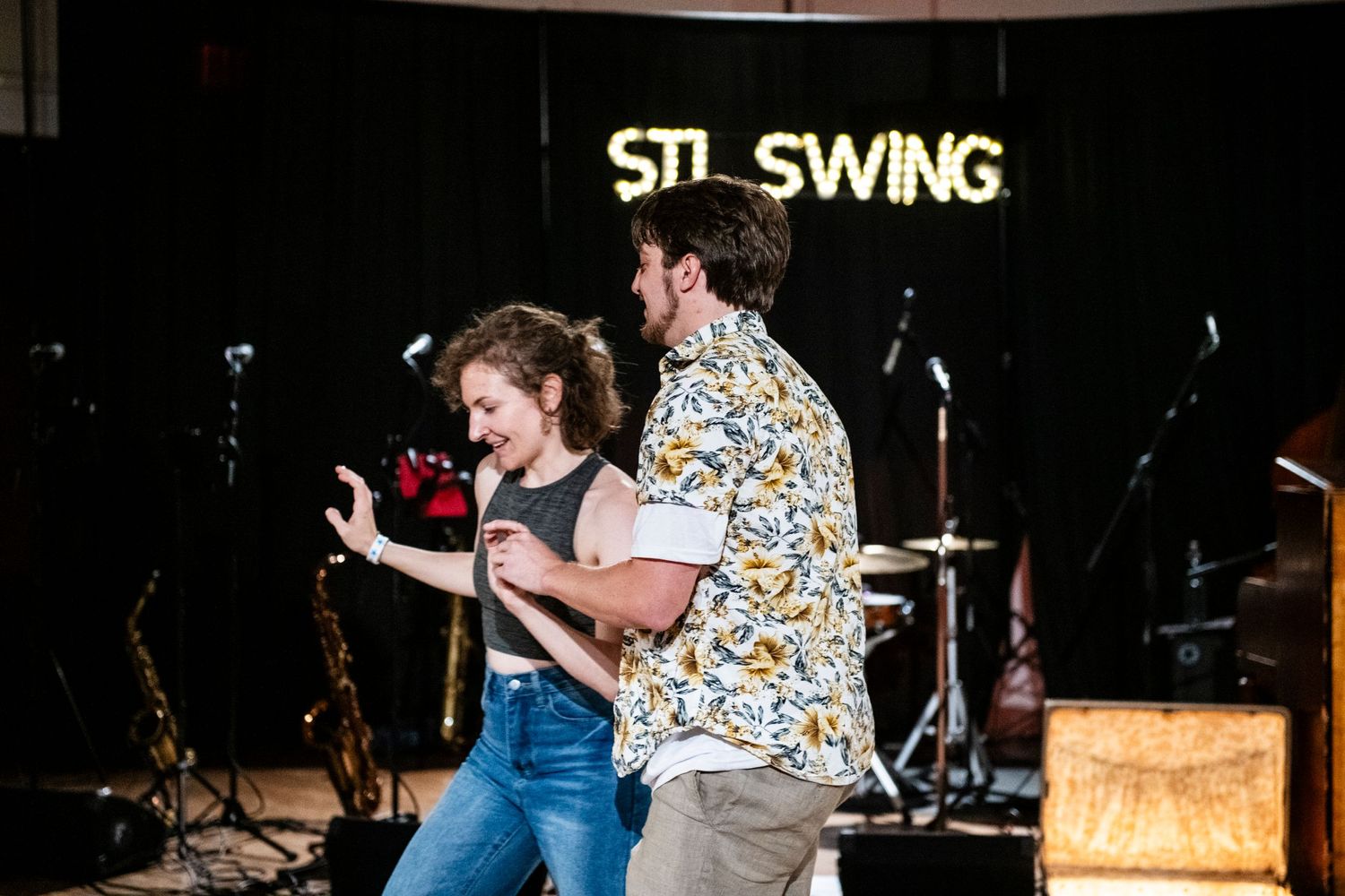 Dancers in casual attire perform dynamic swing dance moves at STL Swing venue.