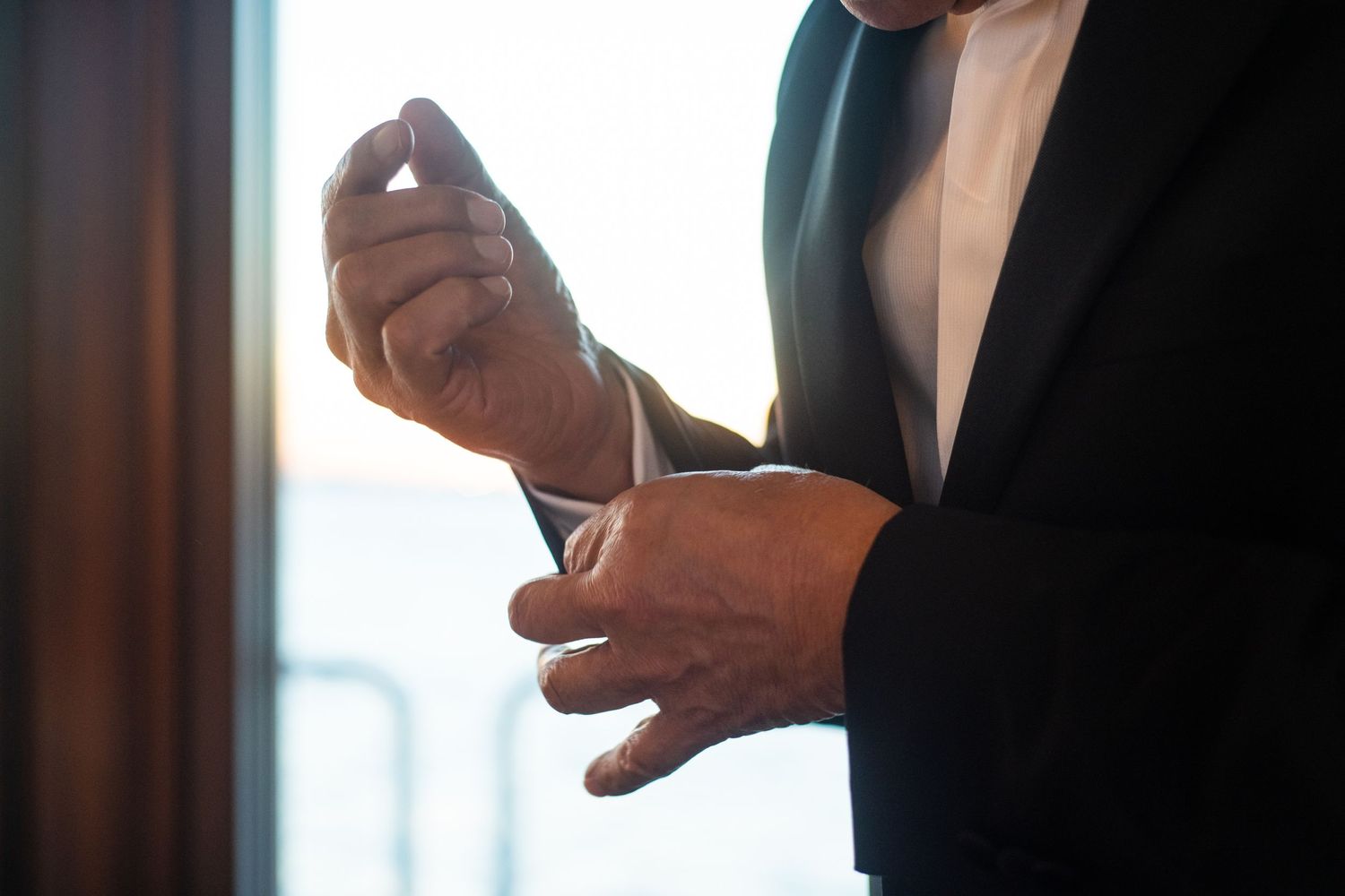 Close-up of hands adjusting formal suit cuffs.