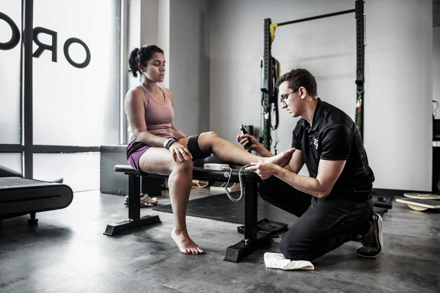 Trainer assessing client's physical condition during rehabilitation session.