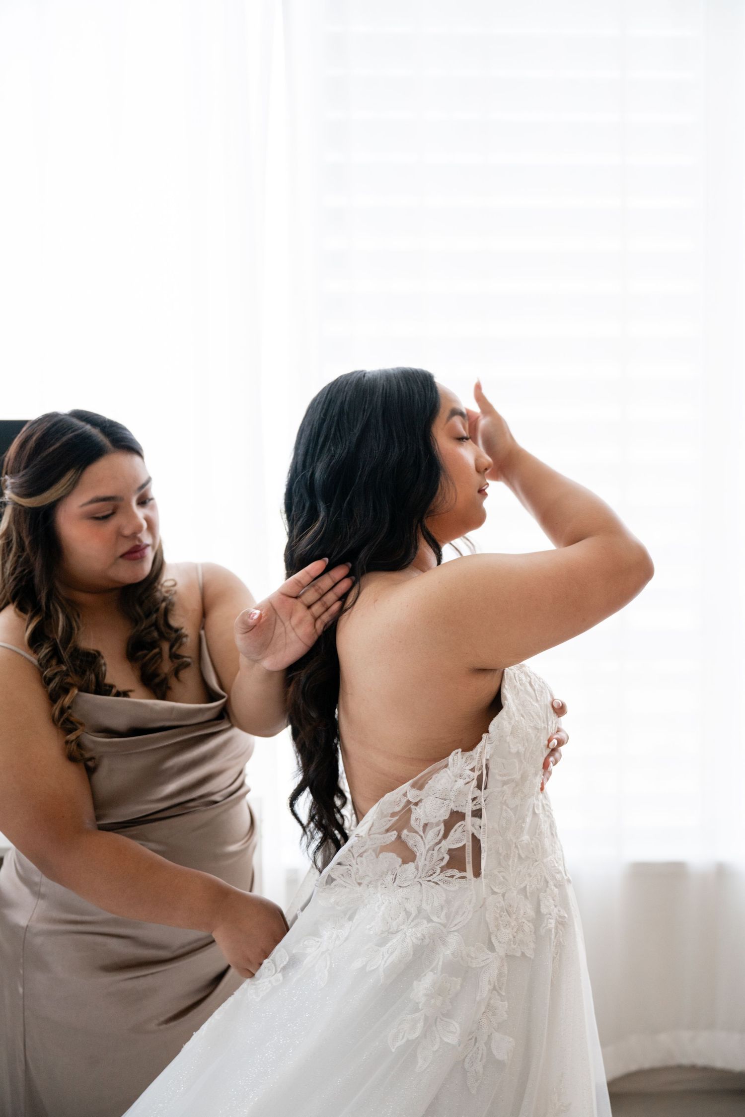 Joyful dancing sequence showing a wedding dress and taupe bridesmaid dress in a bright indoor setting.