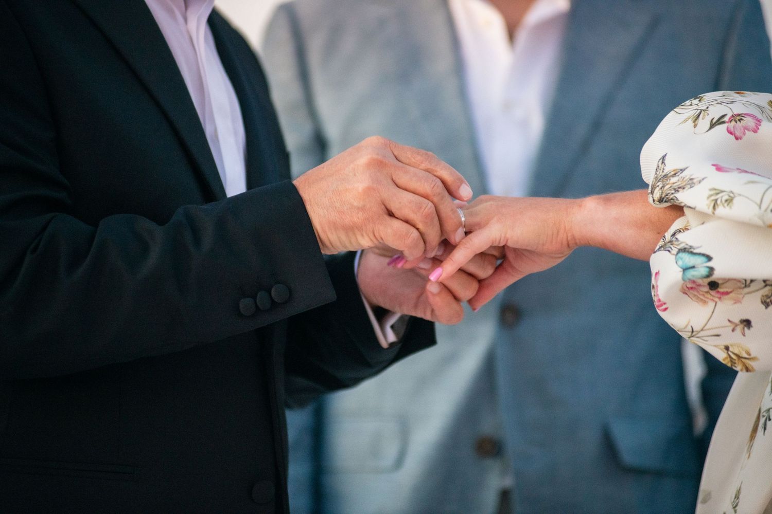 Detailed shot of wedding ring exchange during romantic waterfront ceremony.