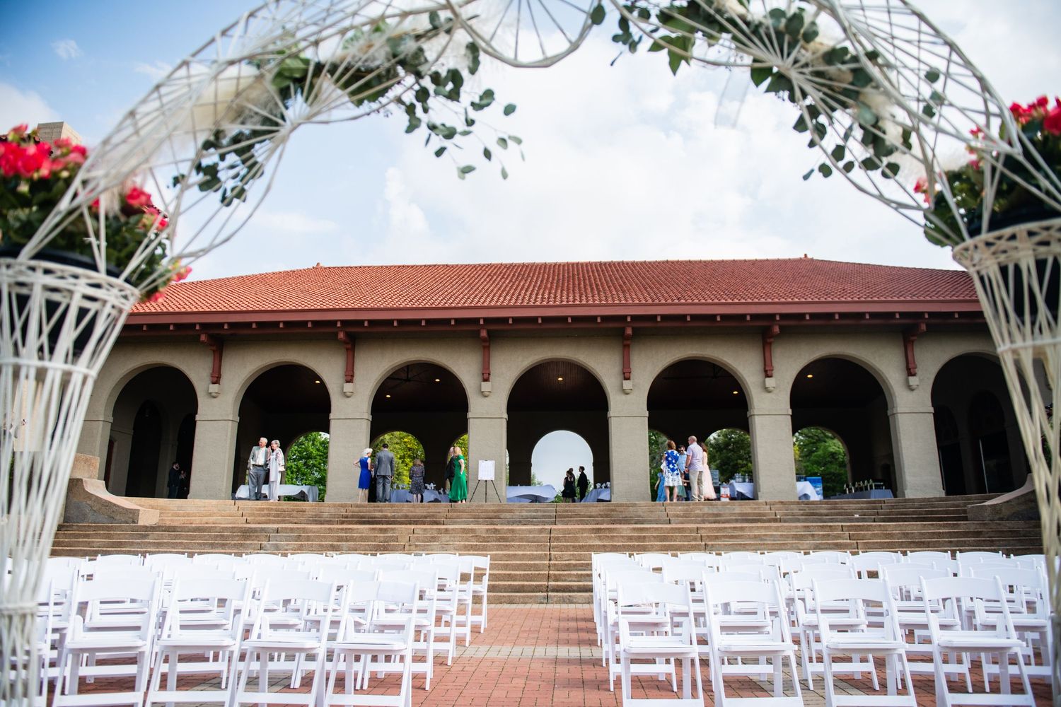 White wedding arch and chairs set up for outdoor ceremony at Mediterranean-style venue.