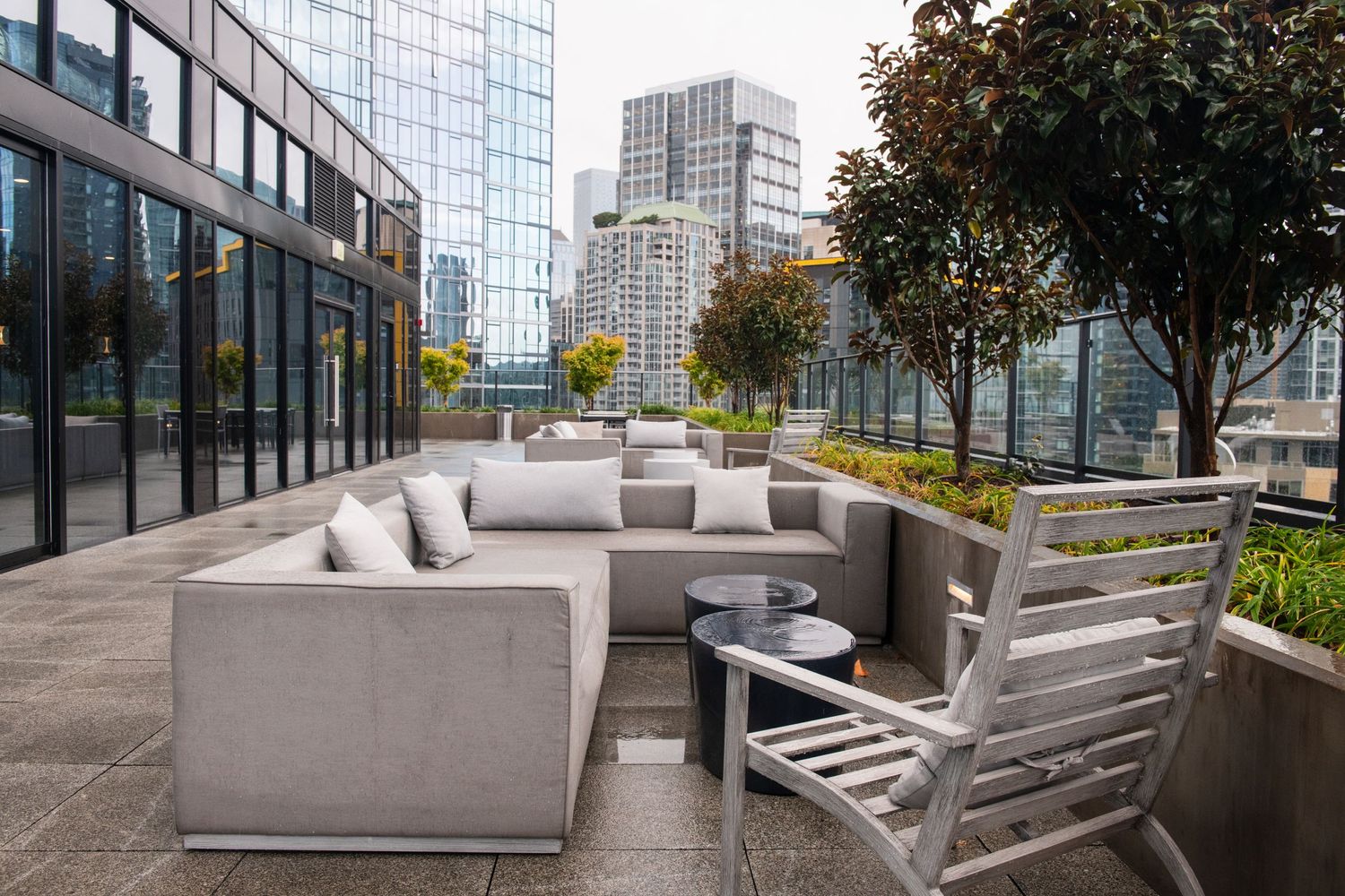 Urban rooftop lounge area with comfortable grey seating and city skyline views.