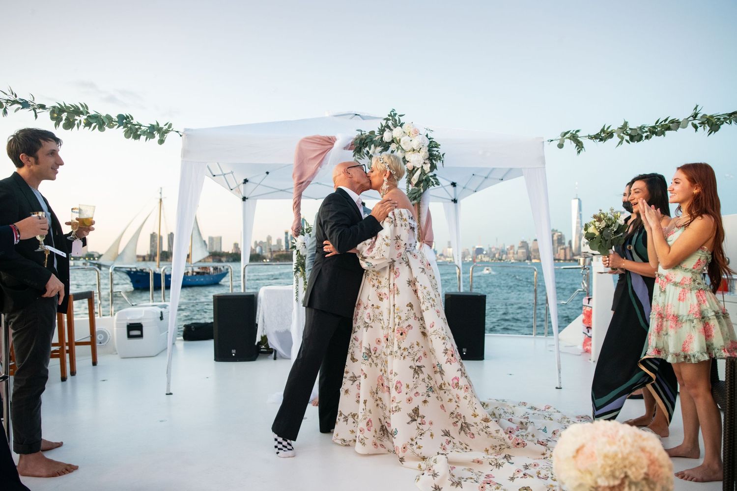 Wedding celebration on boat deck with guests watching first dance under white canopy.