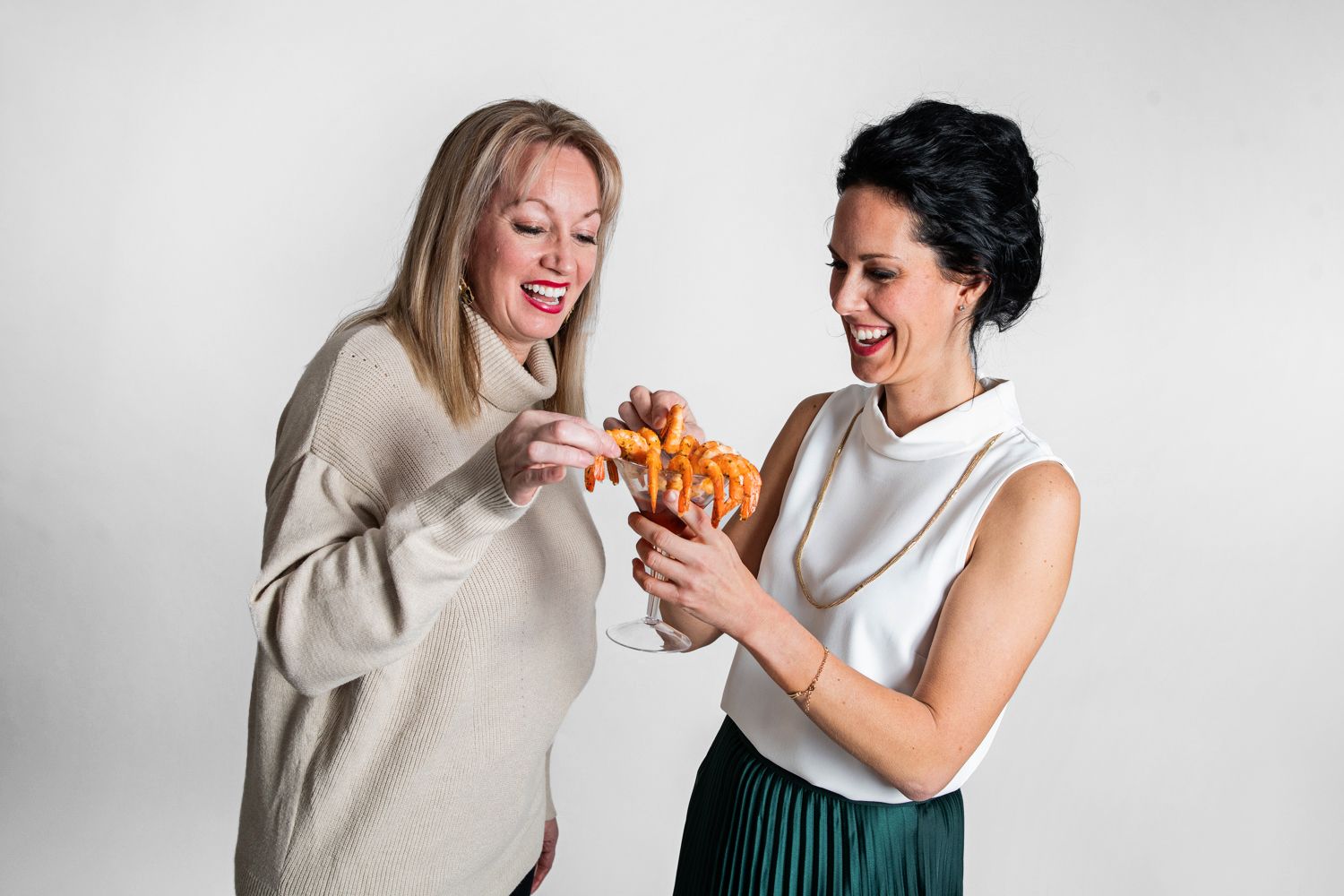 Friends laughing and enjoying a casual dining moment together against white backdrop.