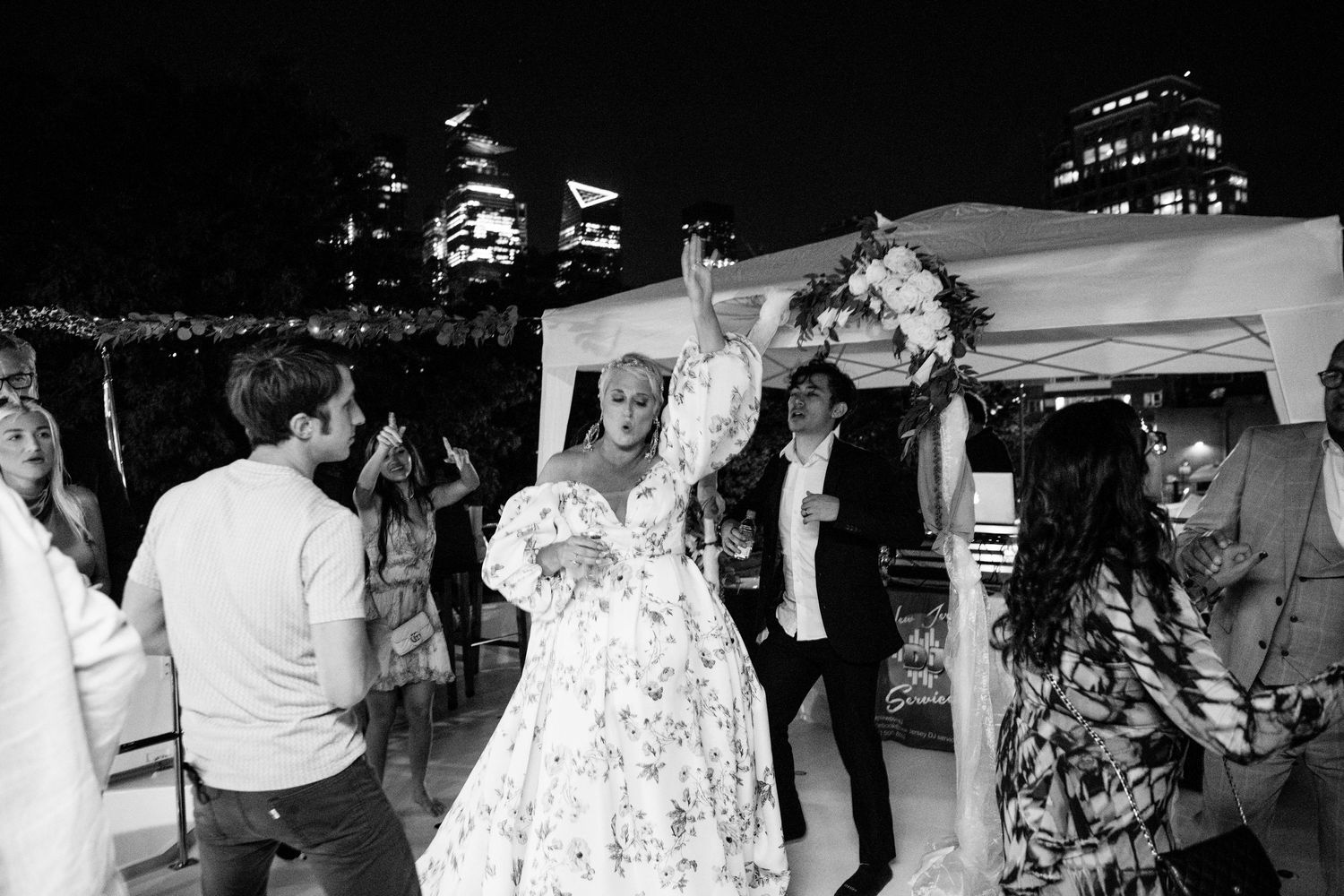 Wedding party dancing and celebrating under lights on boat deck.