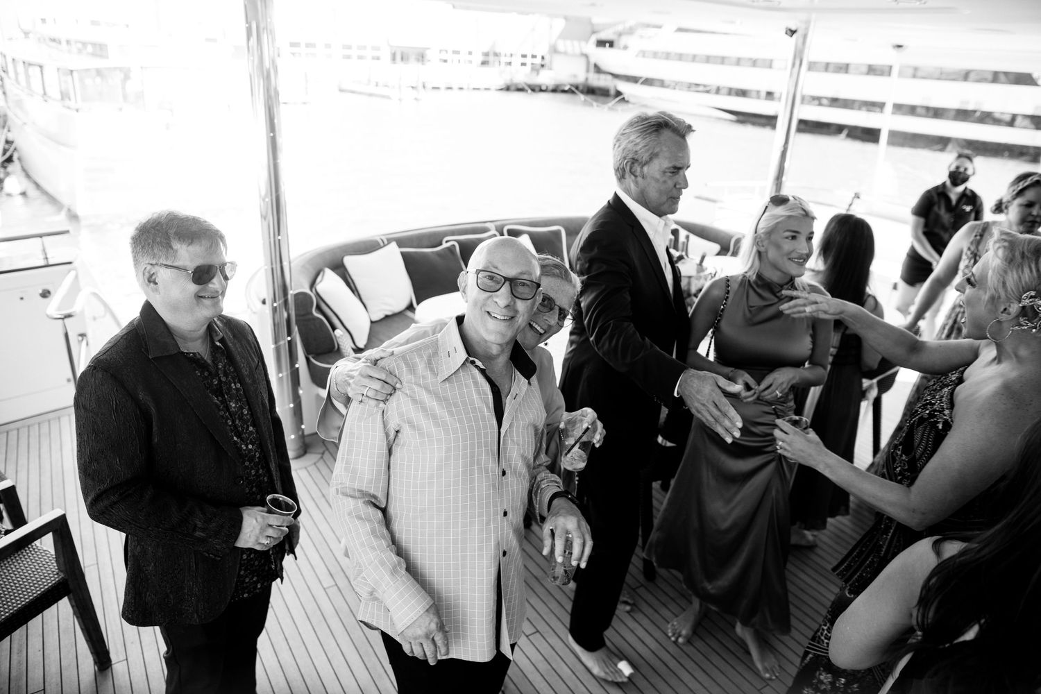 Black and white photo of guests mingling on the deck of a boat party.