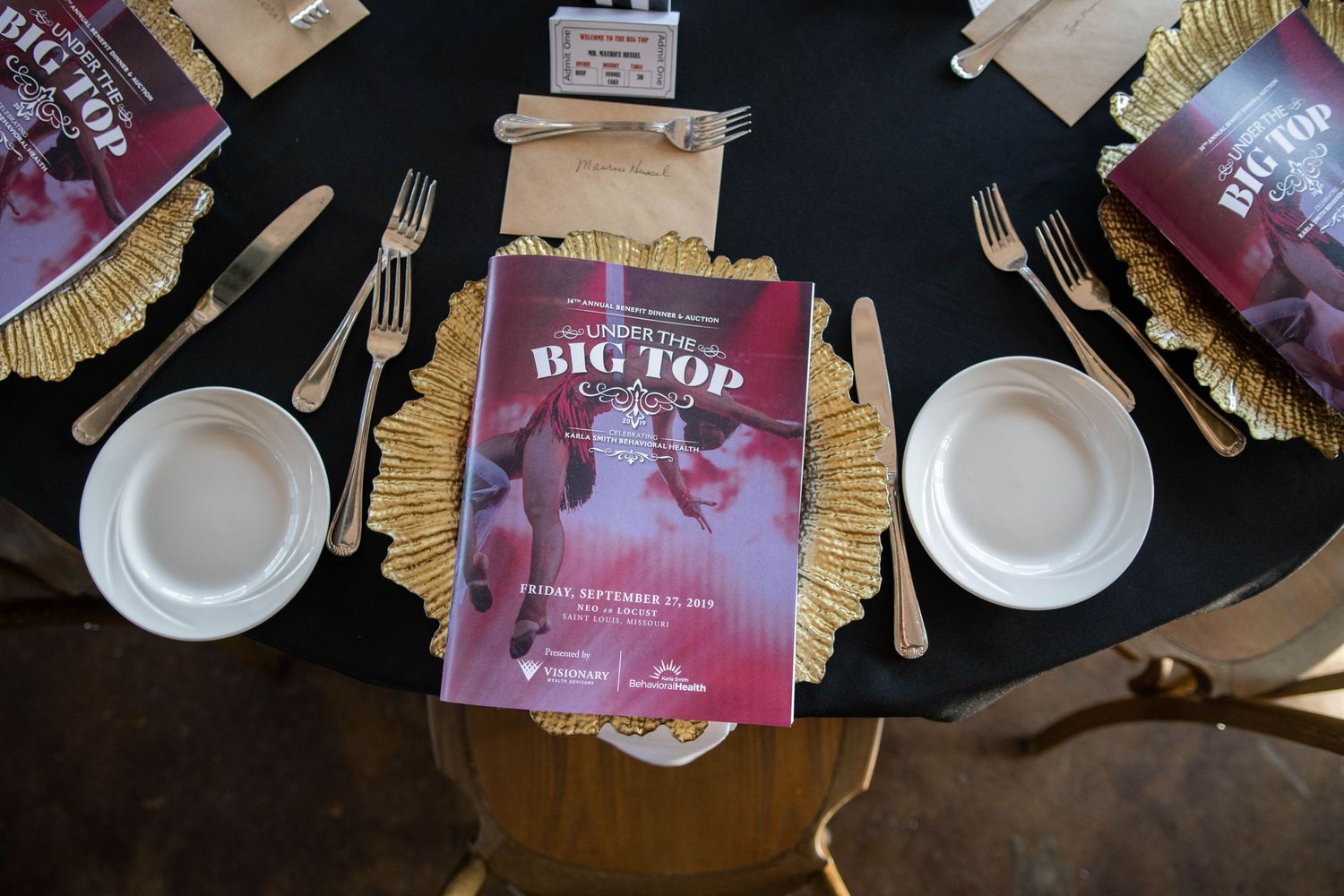 Overhead view of place settings with Big Top programs and gold charger plates.
