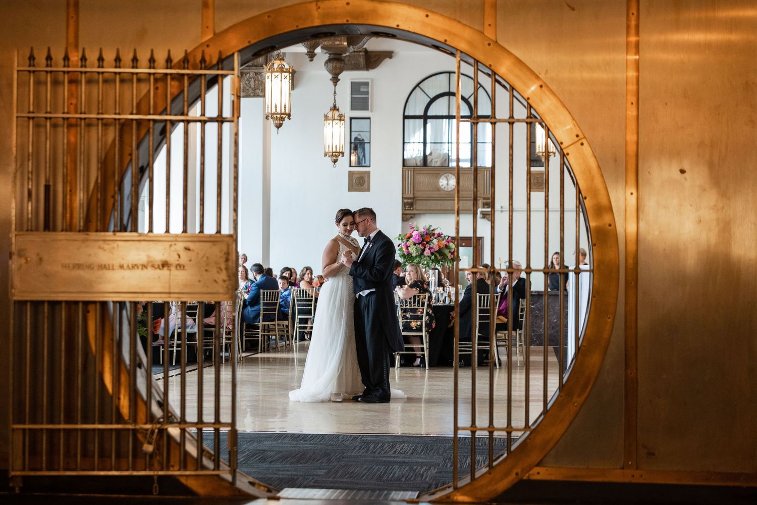 Wedding celebration viewed through circular doorway in ornate venue with architectural details.