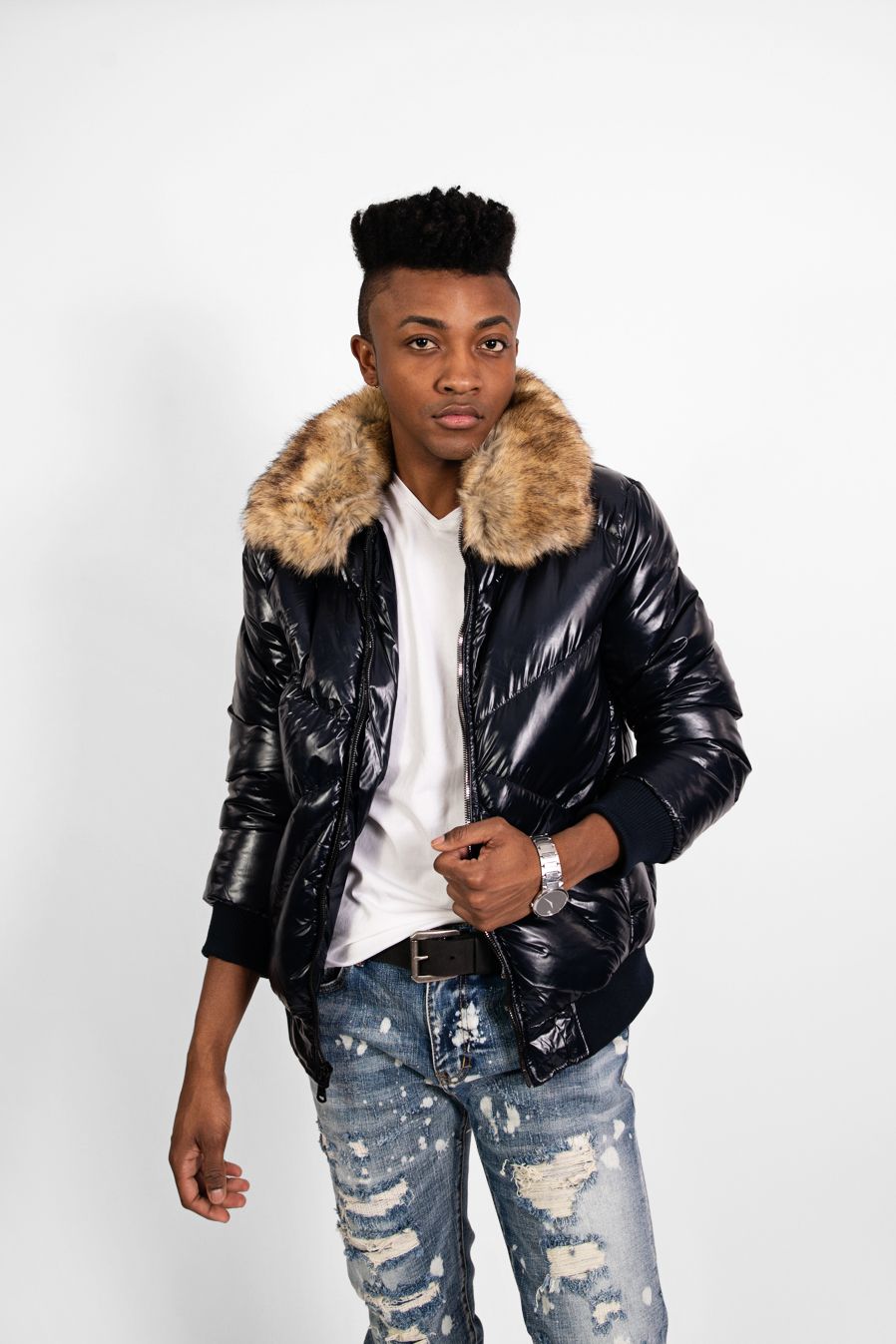Trendy winter outfit featuring black puffer coat with fur collar and ripped jeans.