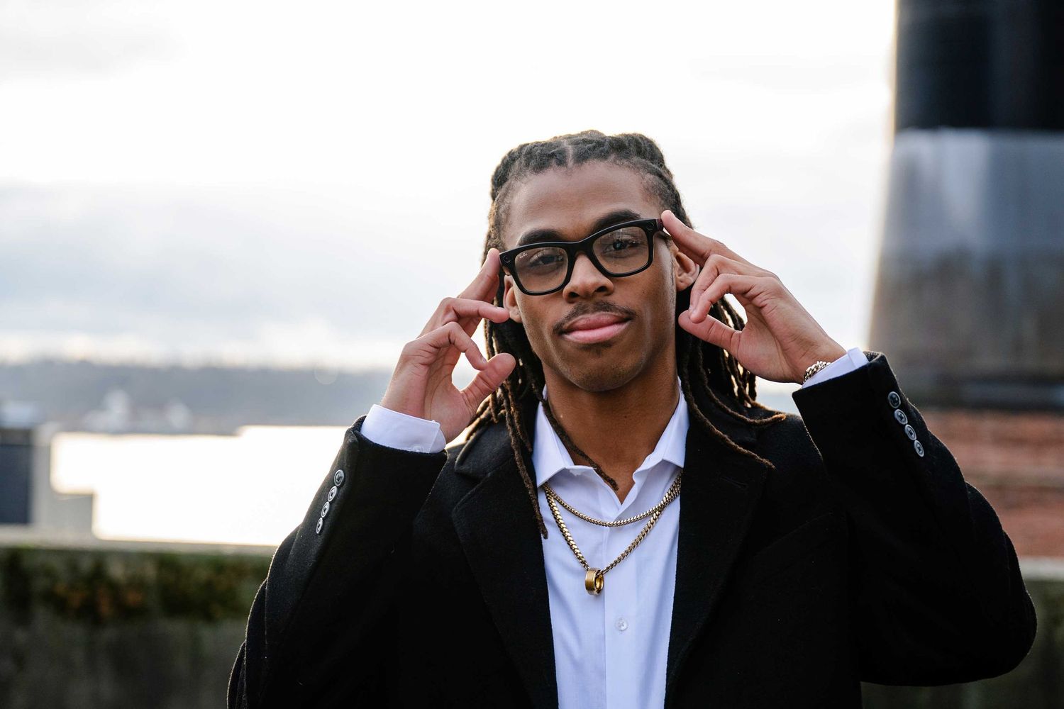 A person in a white dress shirt and dark blazer smiles while speaking on a mobile phone near an office building.