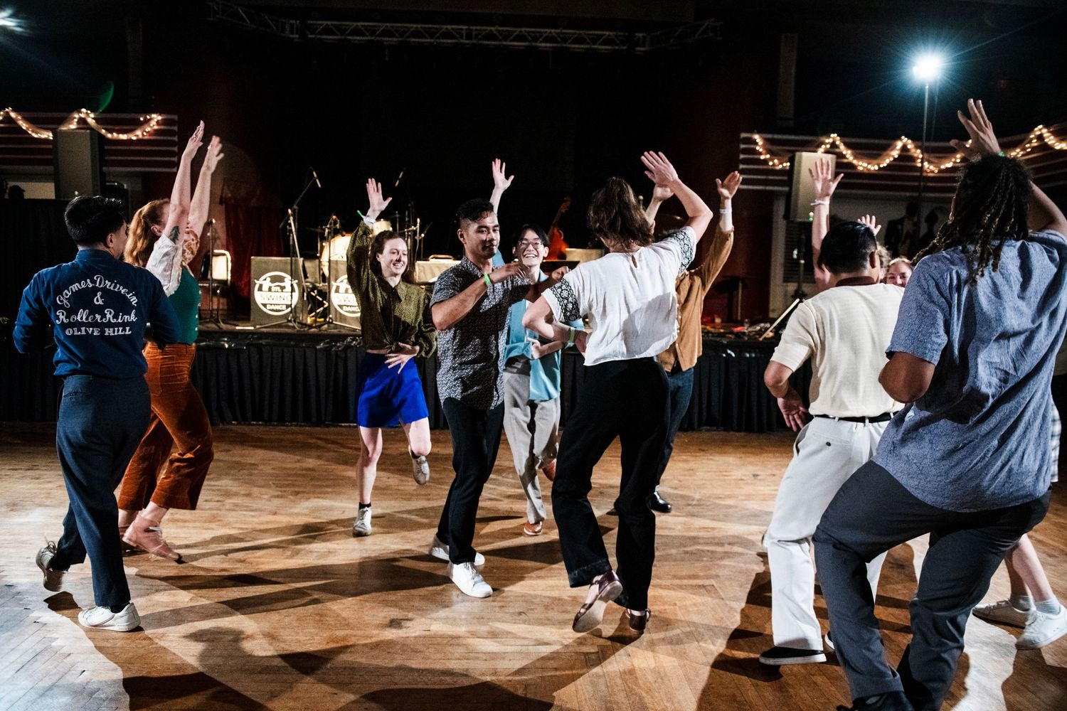 Group of dancers enjoying social swing dancing under stage lighting.