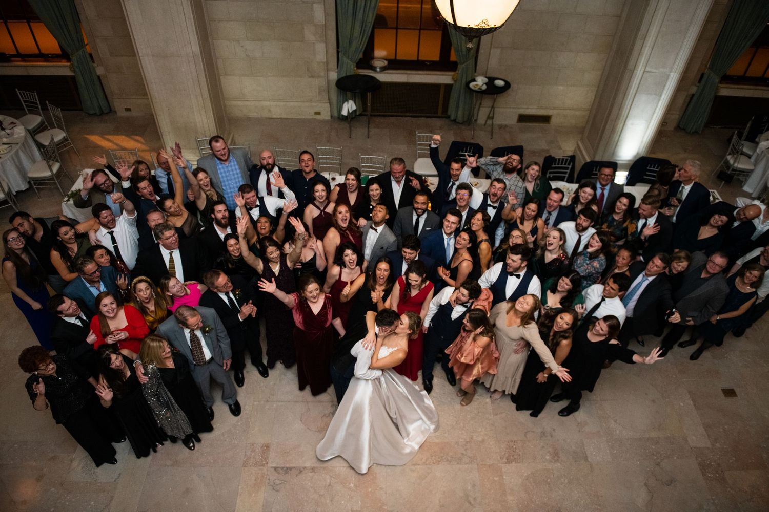 Overhead view of wedding guests gathered in grand ballroom for group photo.