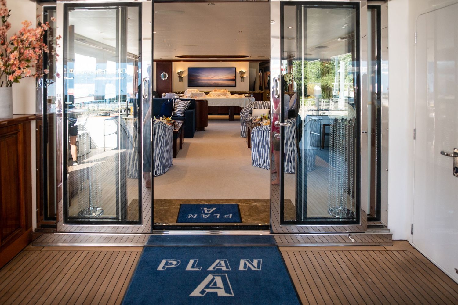 Entrance to yacht interior showing glass doors with 'Plan A' logo on floor mat.