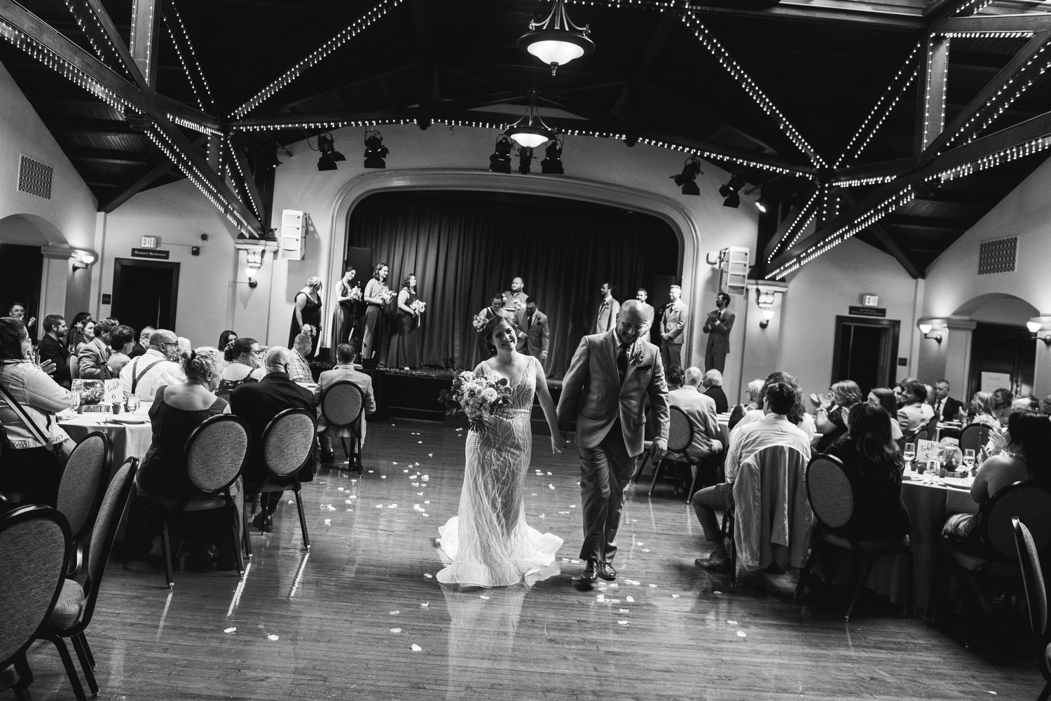 Wedding reception in a historic venue with guests seated at round tables.