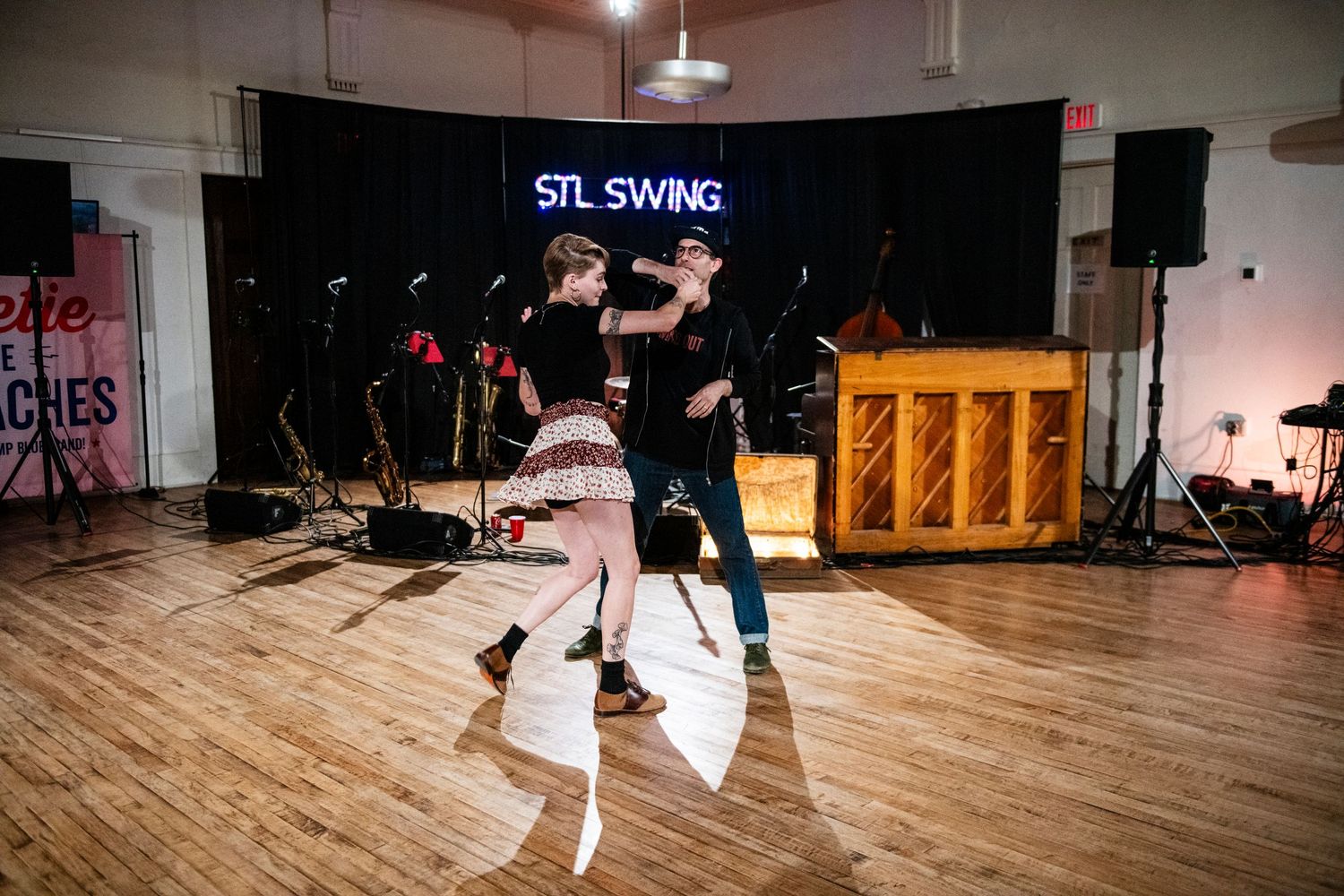 Dancers captured mid-motion during swing dance performance at STL venue.