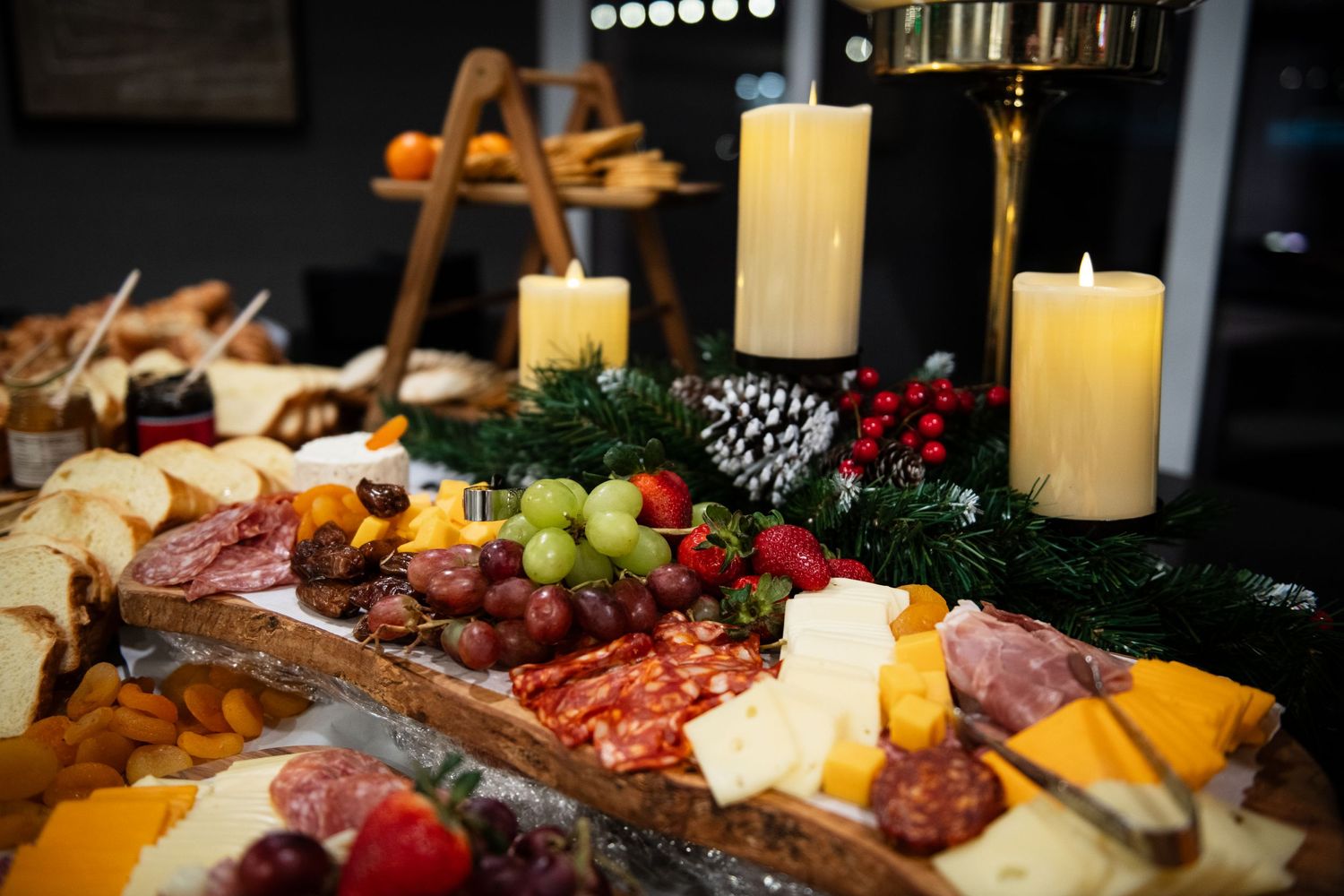 Elegant charcuterie board with meats, cheeses, fruits and lit candles for holiday entertaining.