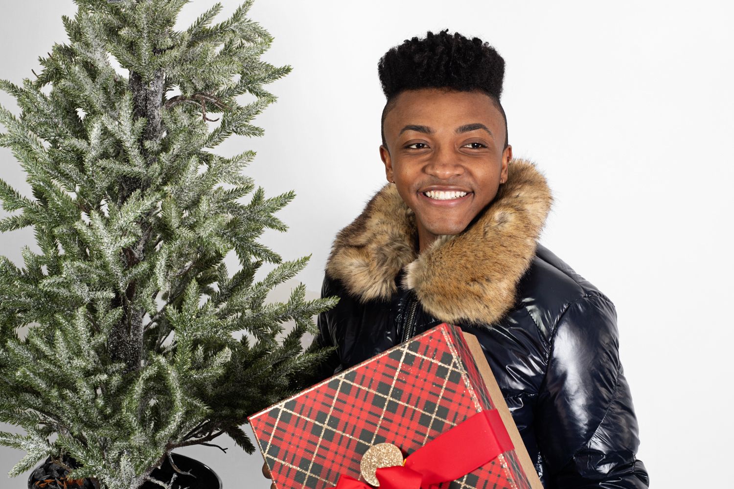 Festive winter fashion scene with decorated tree and holiday gift.