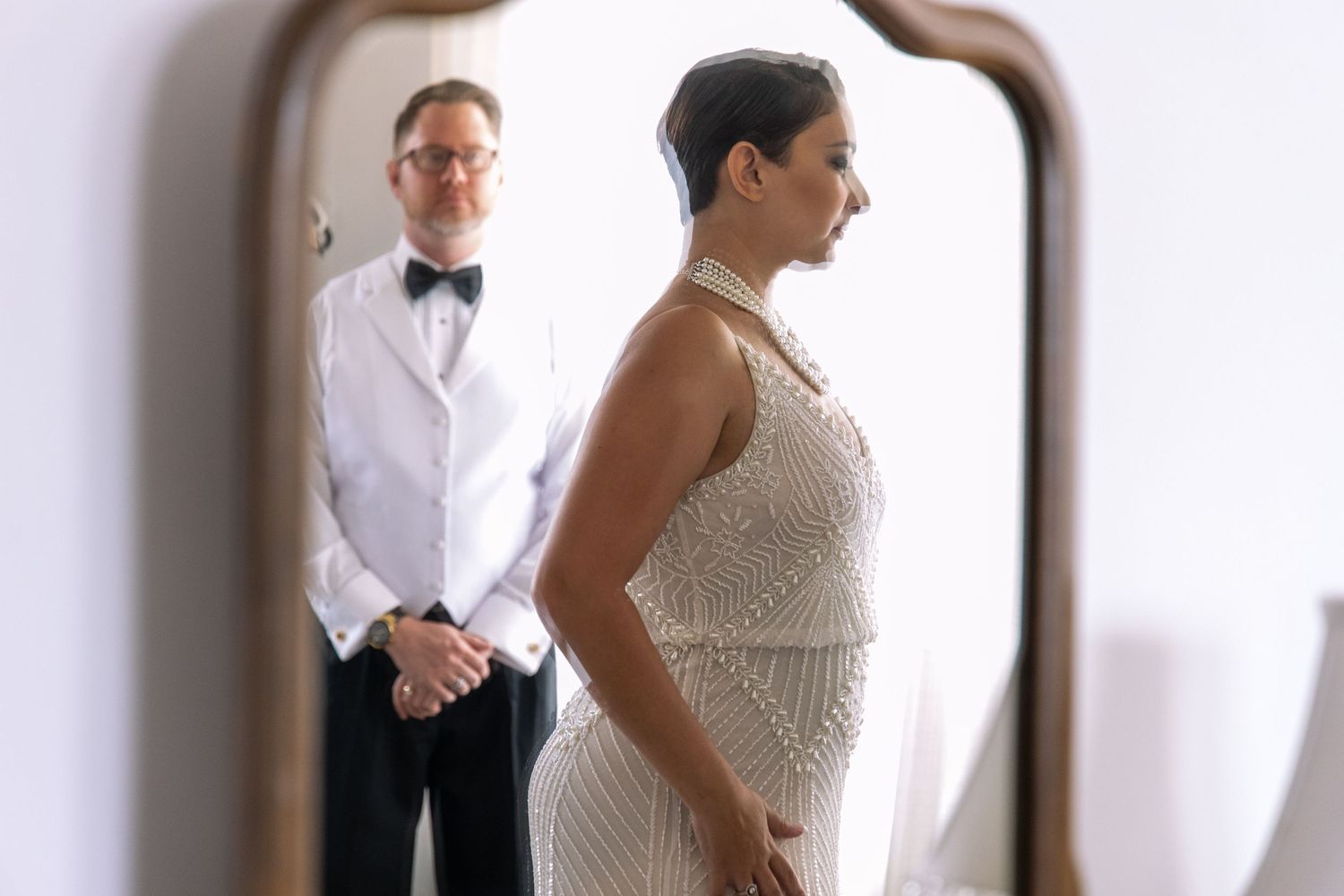 Wedding day reflection captured in vintage mirror showing formal attire and anticipation.