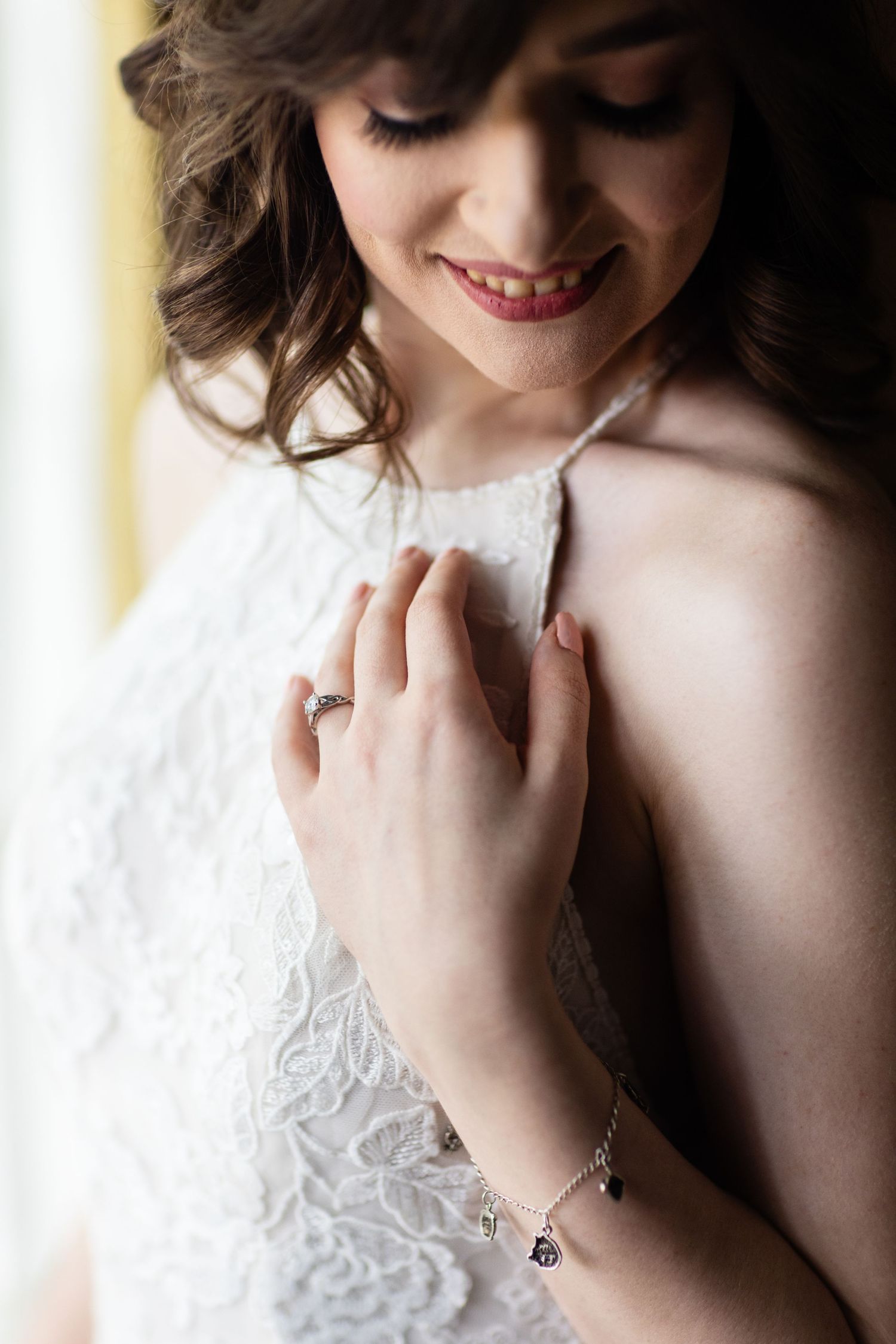 Intimate portrait showing delicate lace detail and jewelry against white fabric.